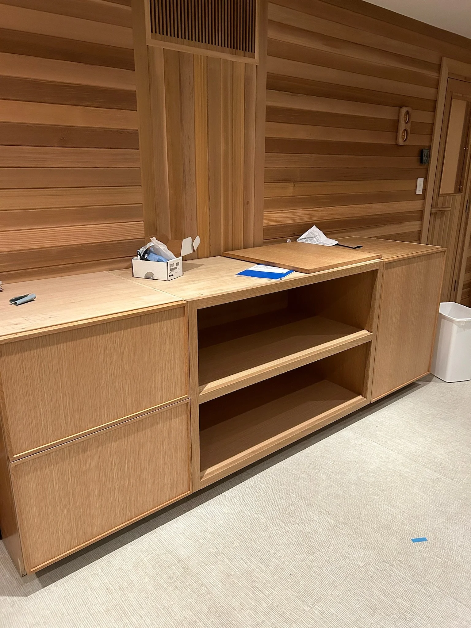 Empty wooden sideboard and shelves in a room with wooden walls and a light-colored carpet.