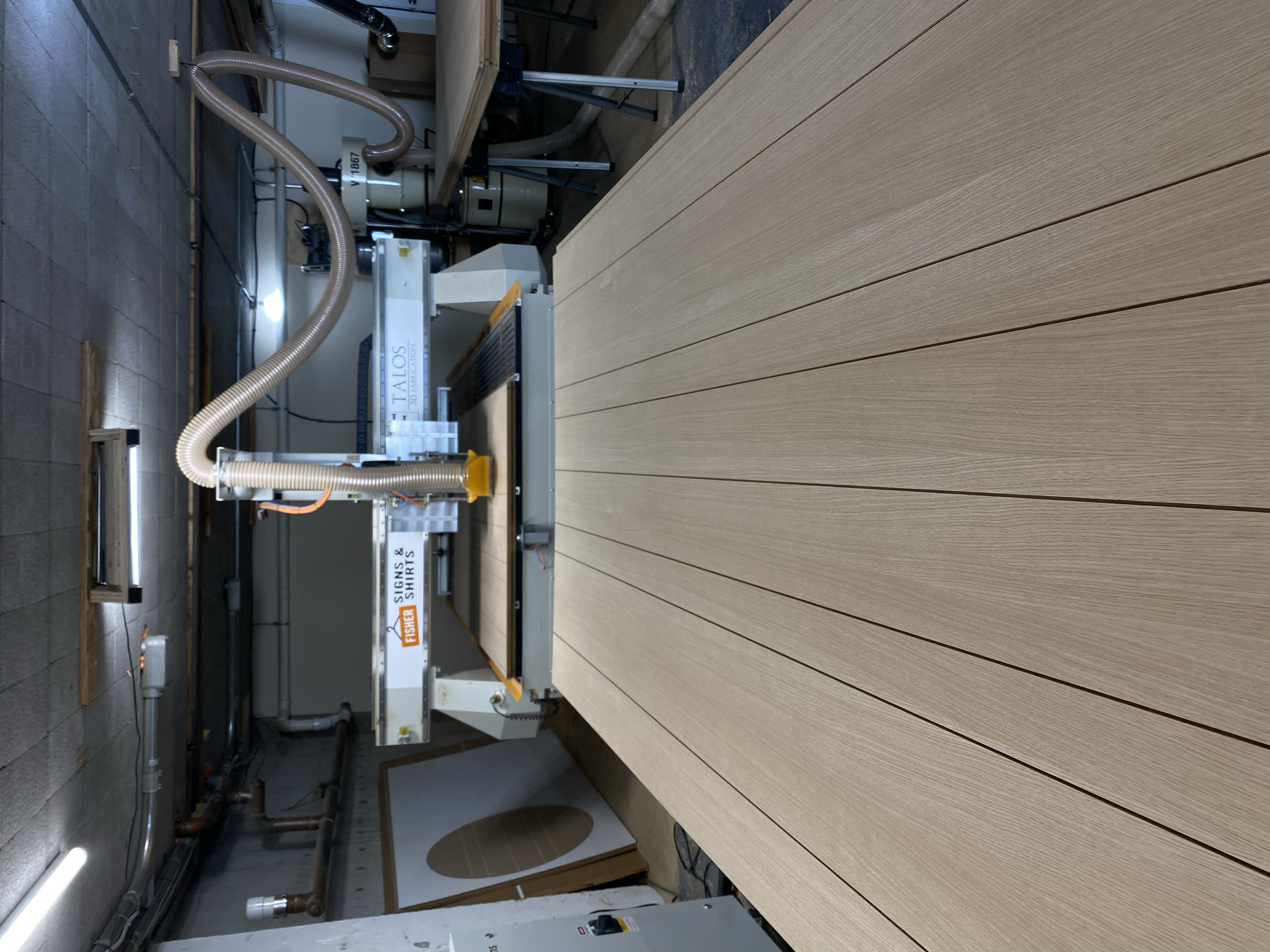 Woodworking CNC machine carving long, thin wooden planks in a workshop.