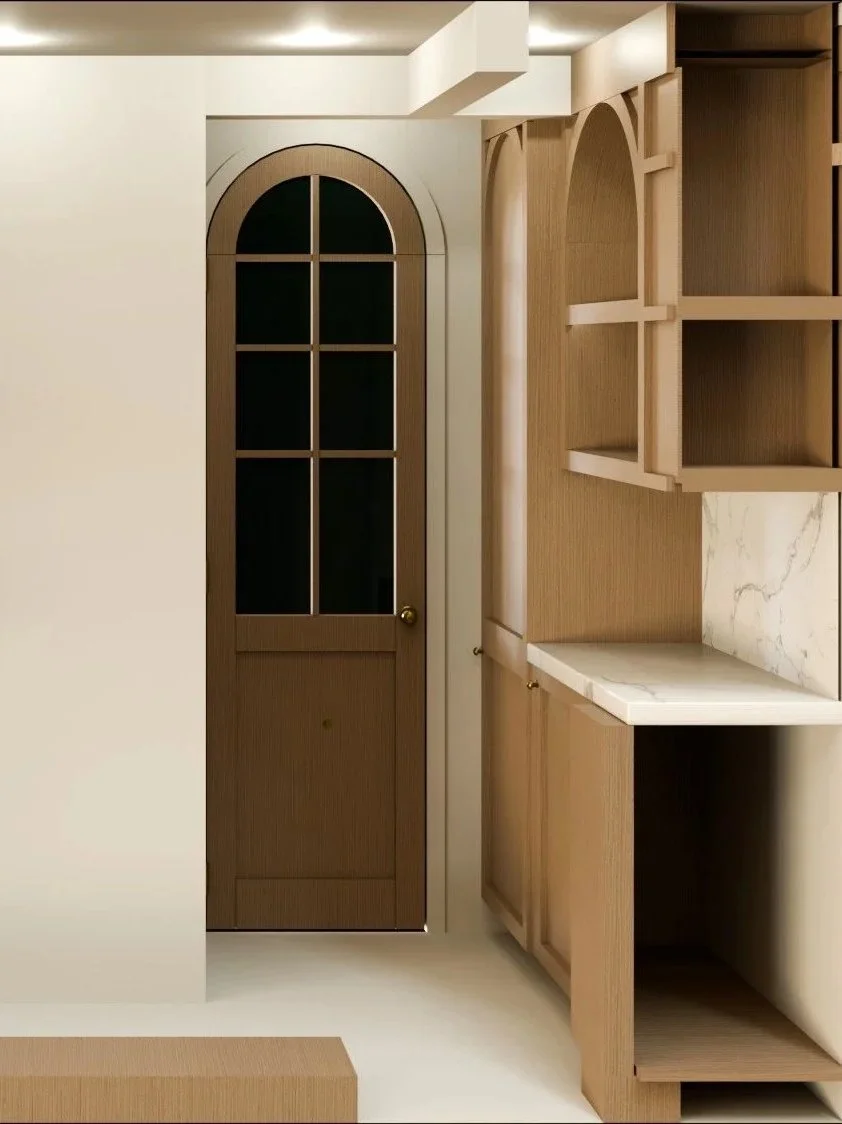 Interior view of a room with a brown wooden door with glass panes and a brass knob, white walls, and built-in wooden shelving with marble countertop.