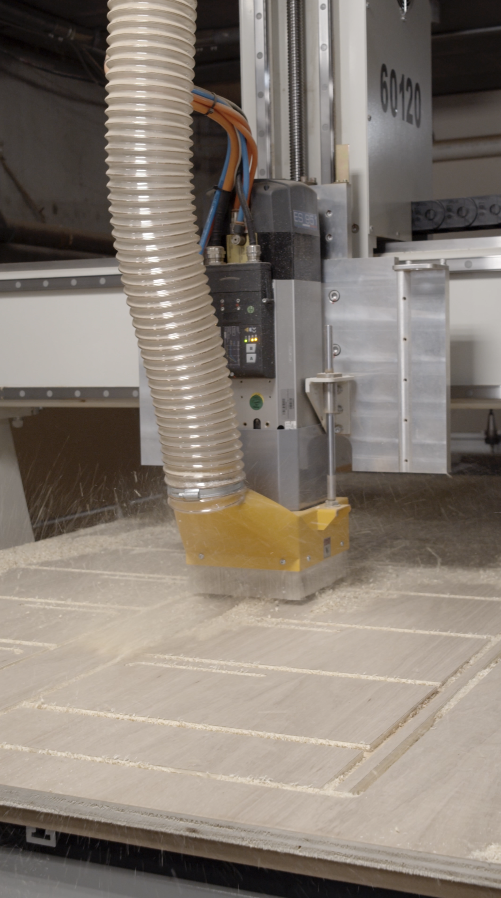 A CNC machine routing or carving a pattern into a wooden surface in a workshop.