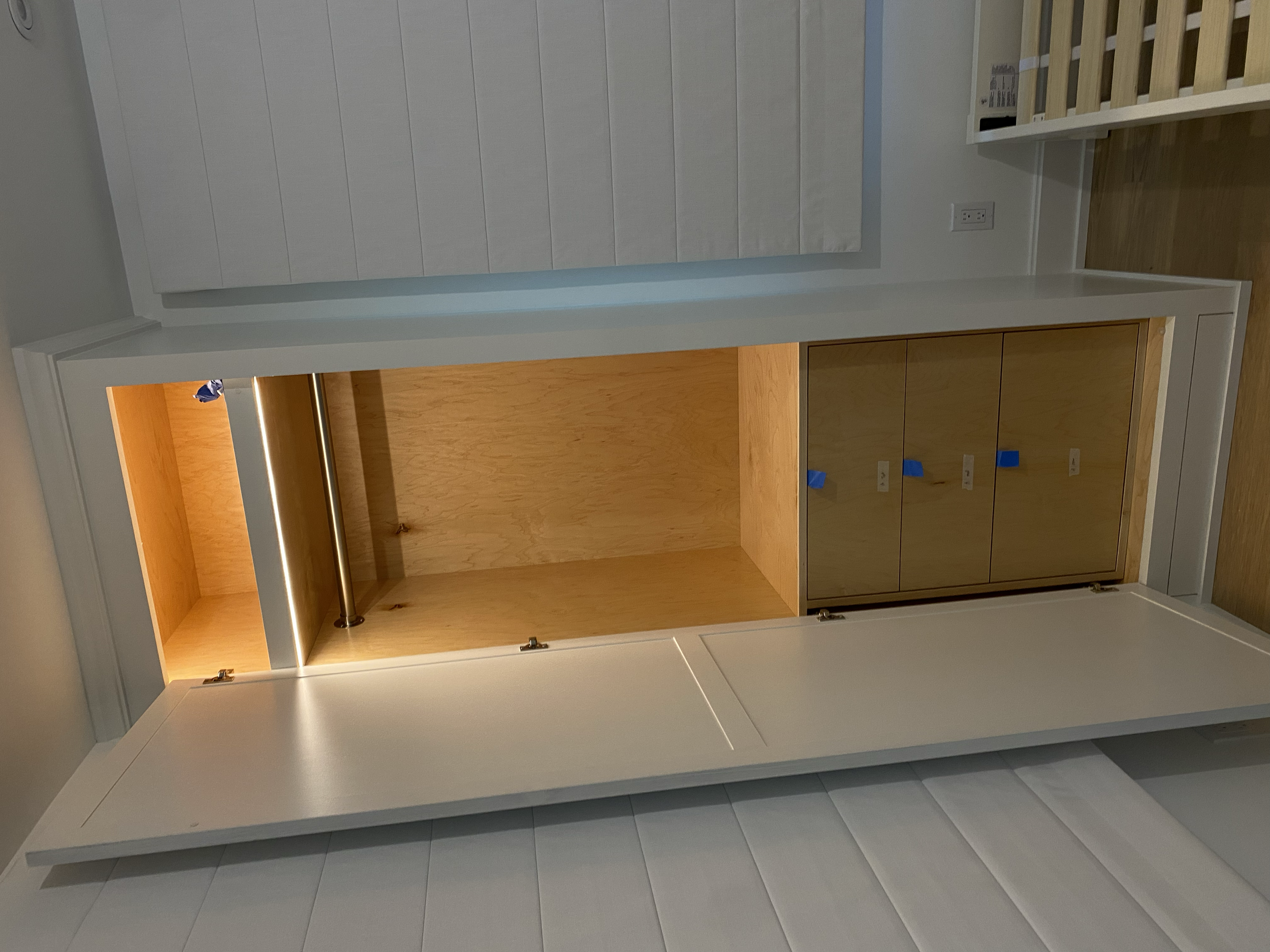 Empty built-in wooden cabinet in a room with wooden flooring and white walls. Custom.