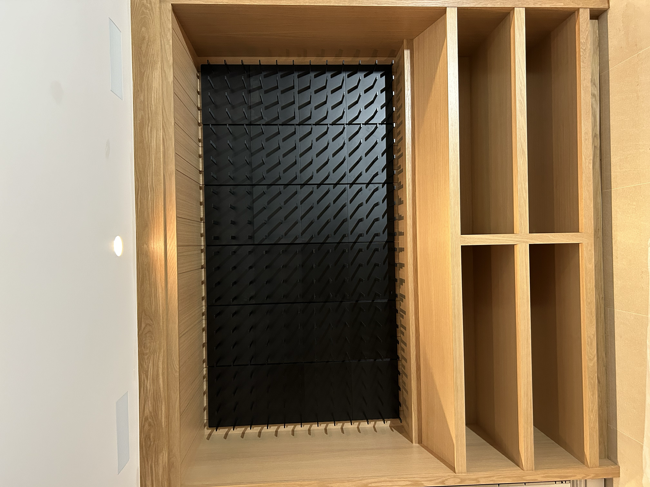 Open wooden shelving unit with multiple compartments and a black grid-like structure inside the upper section.
