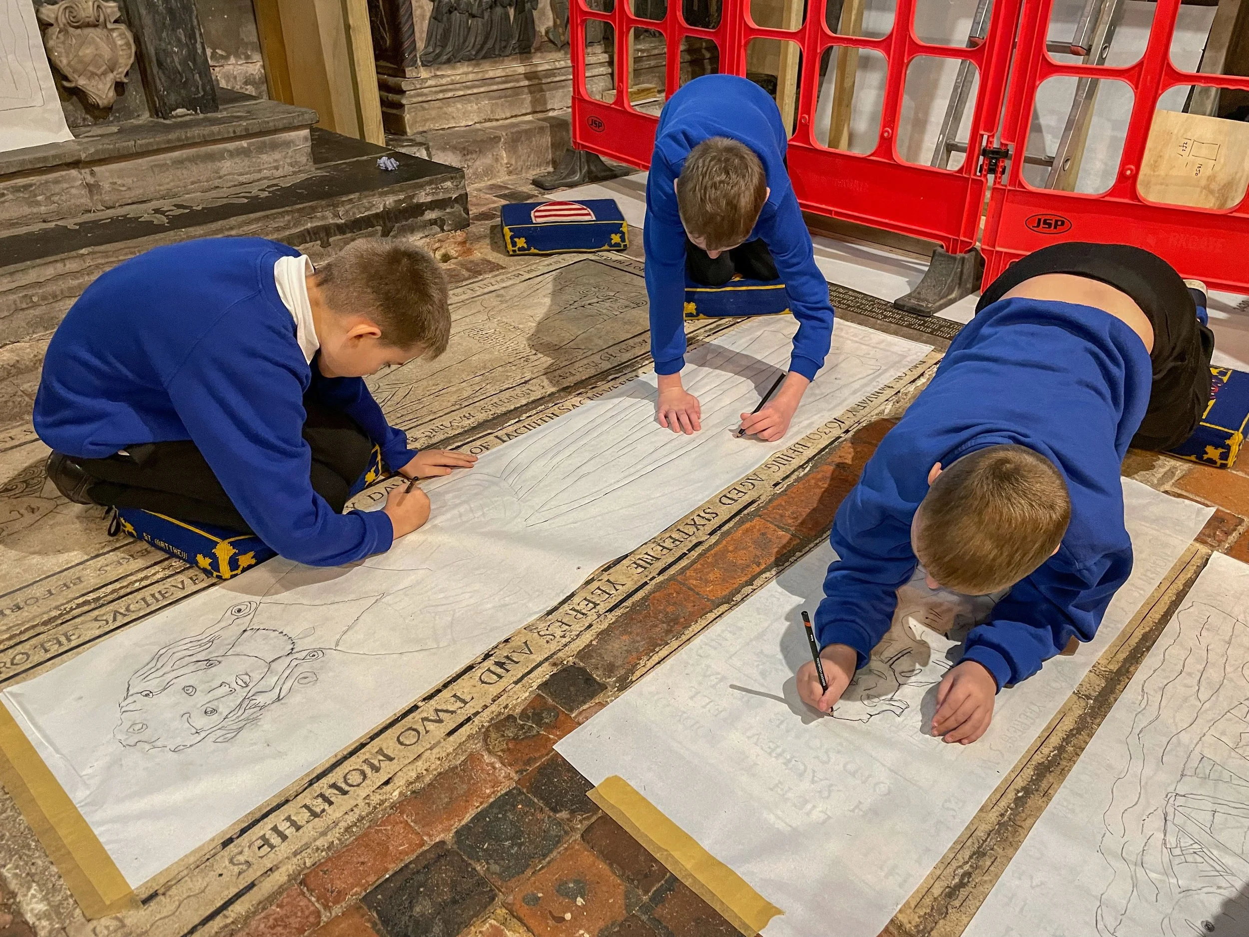 Pupils tracing medieval tiles in a church