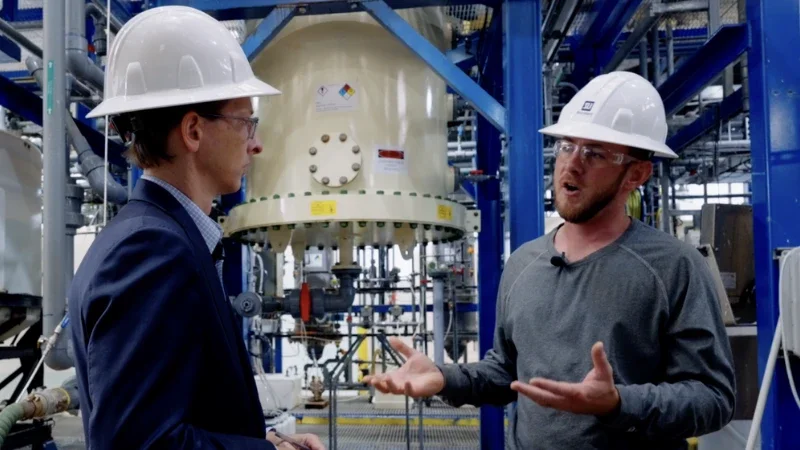 Projects category: two men in hardhats and glasses talking in a factory