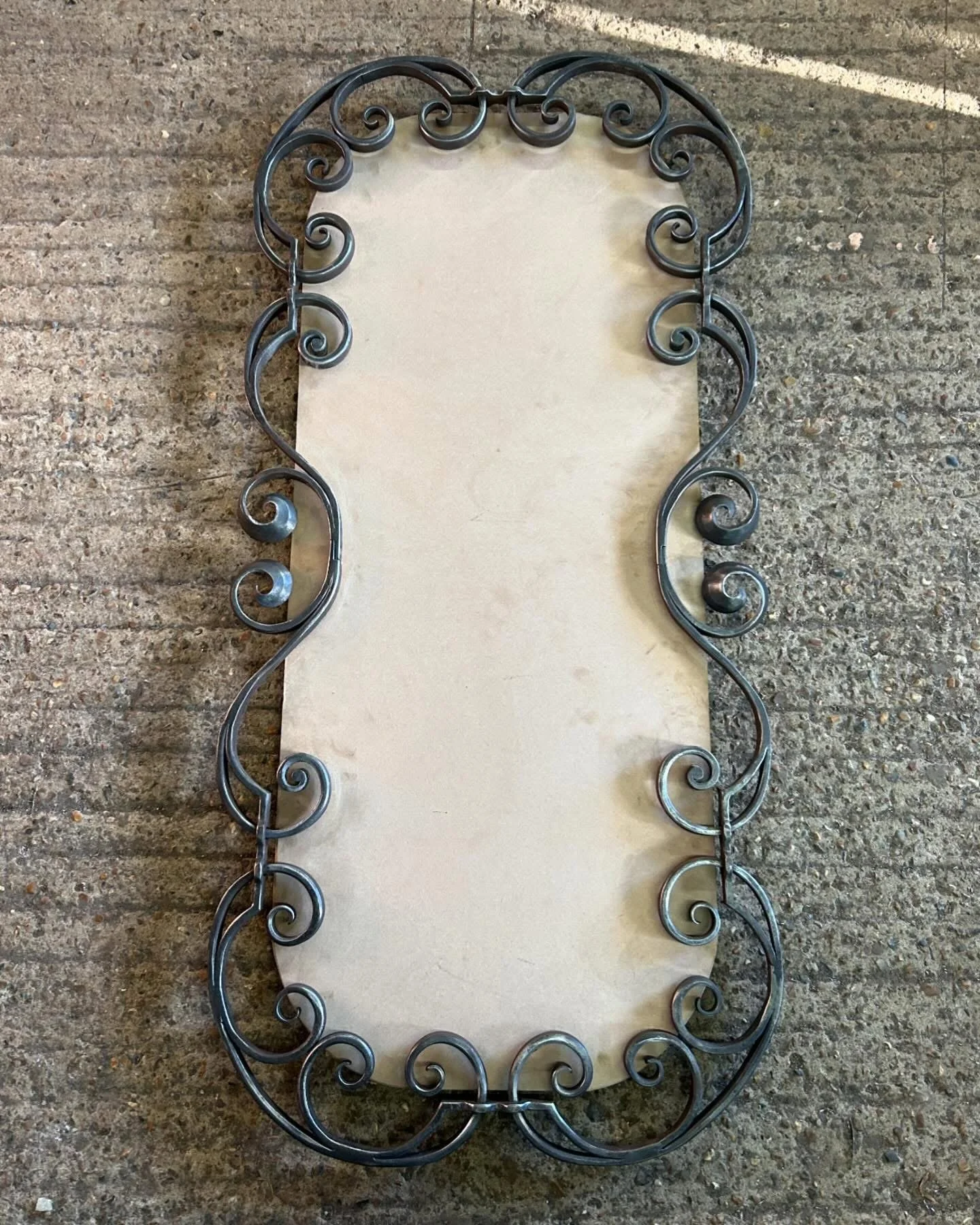 Bespoke mirror frame during manufacture, showing individually hand-forged steel scrolls assembled using traditional blacksmithing techniques.