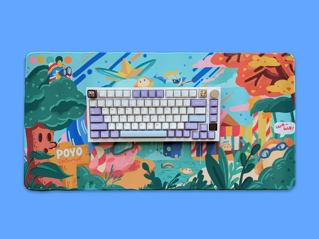 Colorful illustrated desk mat with a computer keyboard on top, featuring cartoonish trees, animals, and scenes from POYO island, with a blue background.