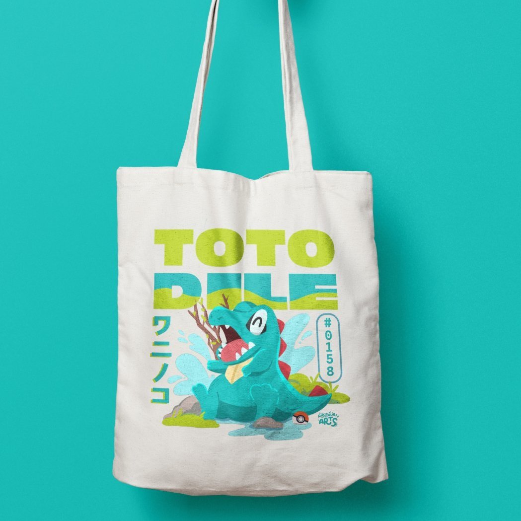 Tote bag with Totodile Pokémon design, featuring colorful illustration and text including Pokémon number 0158, on a teal background.
