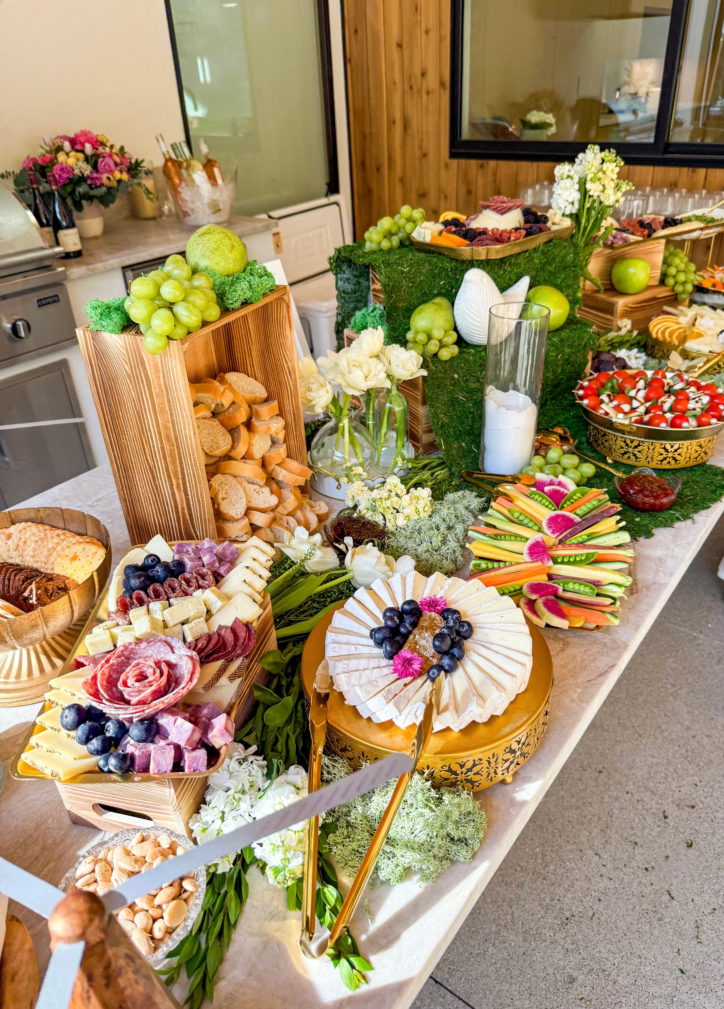 Grazing table with wooden crates and green and gold accents in natural light