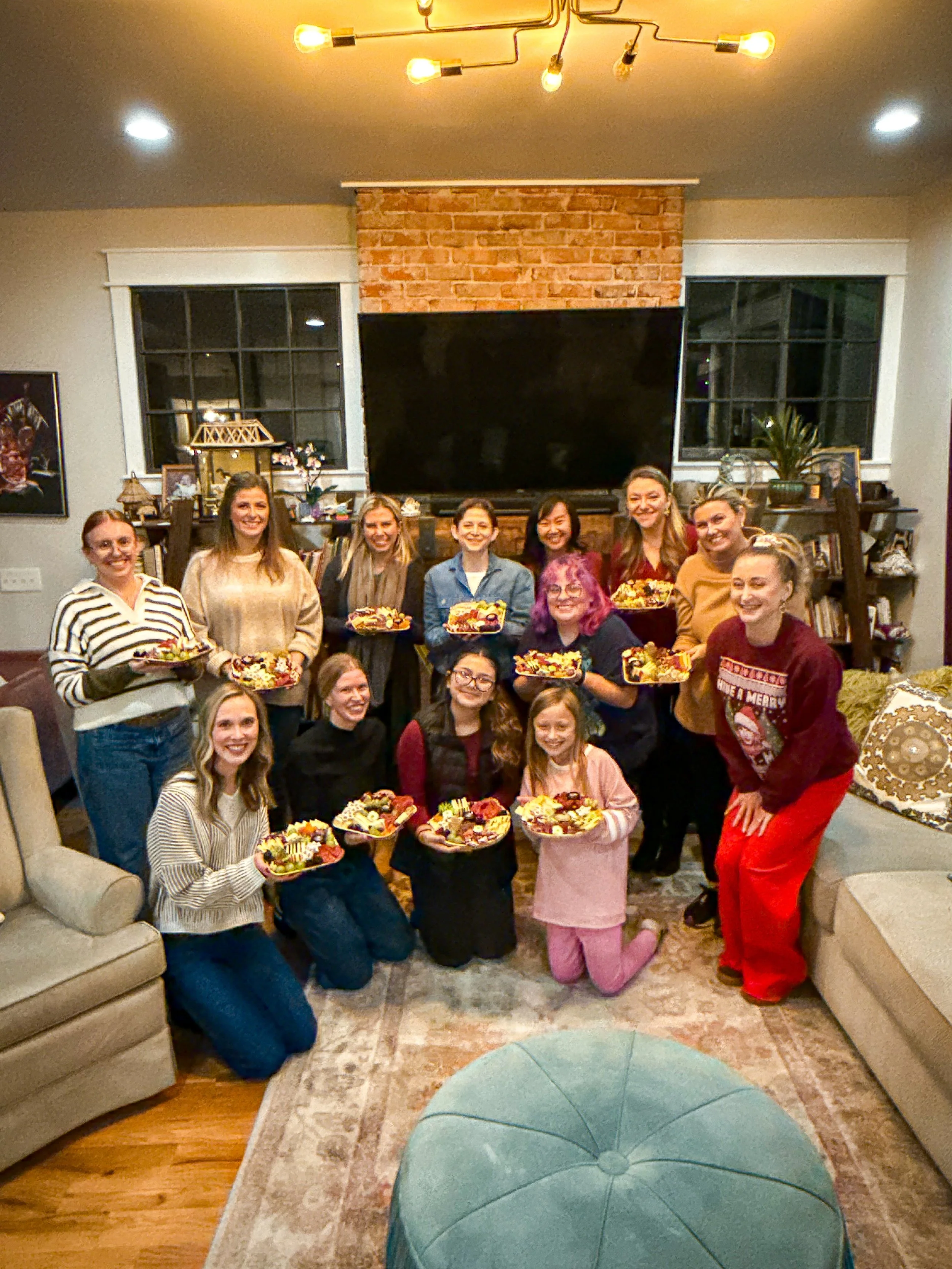 Group of 12 women holding charcuterie boards they made in a workshop