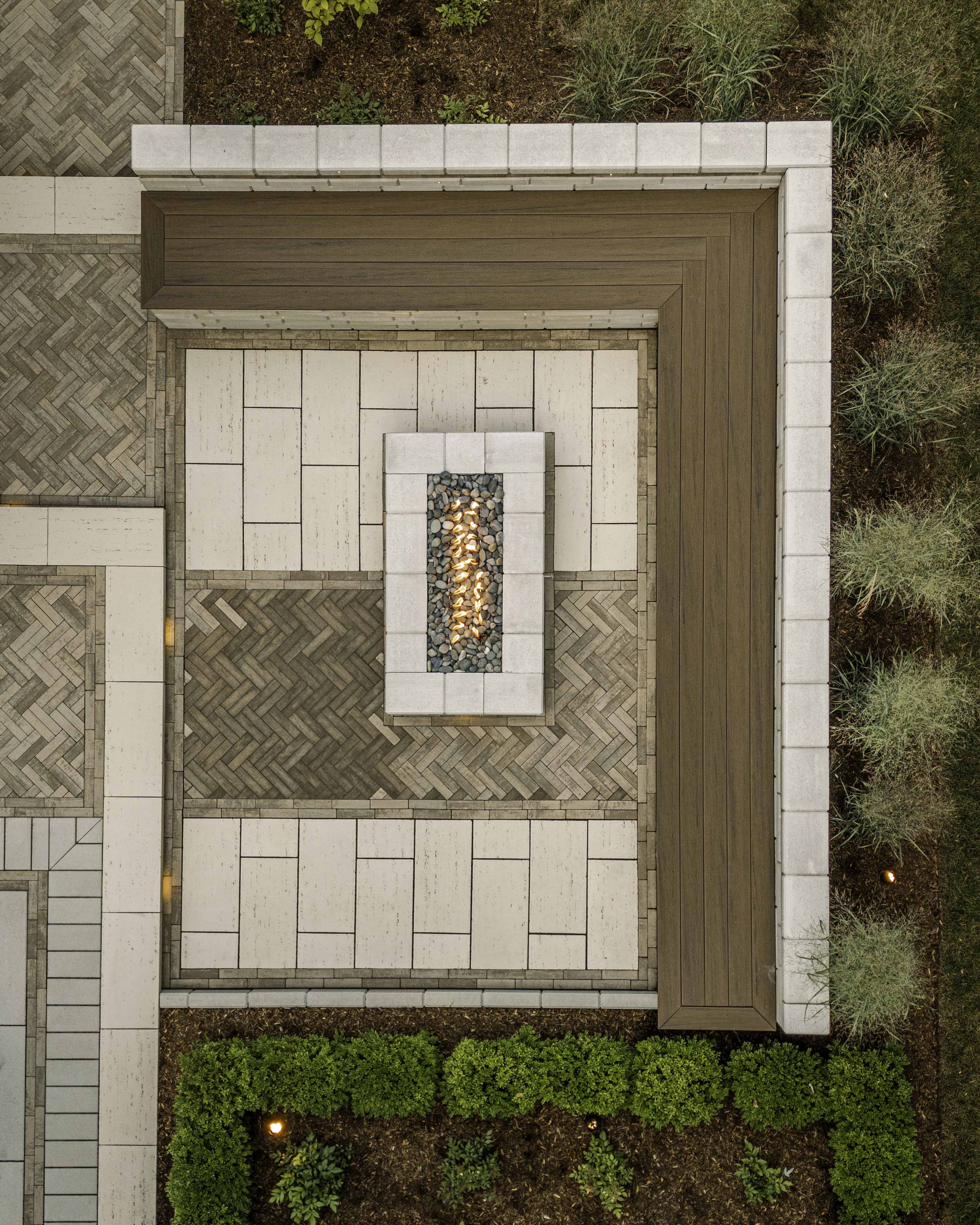 Outdoor patio with manufactured Techo-Bloc pavers and steps, integrated lighting, and landscaped garden featuring small plants and shrubs.