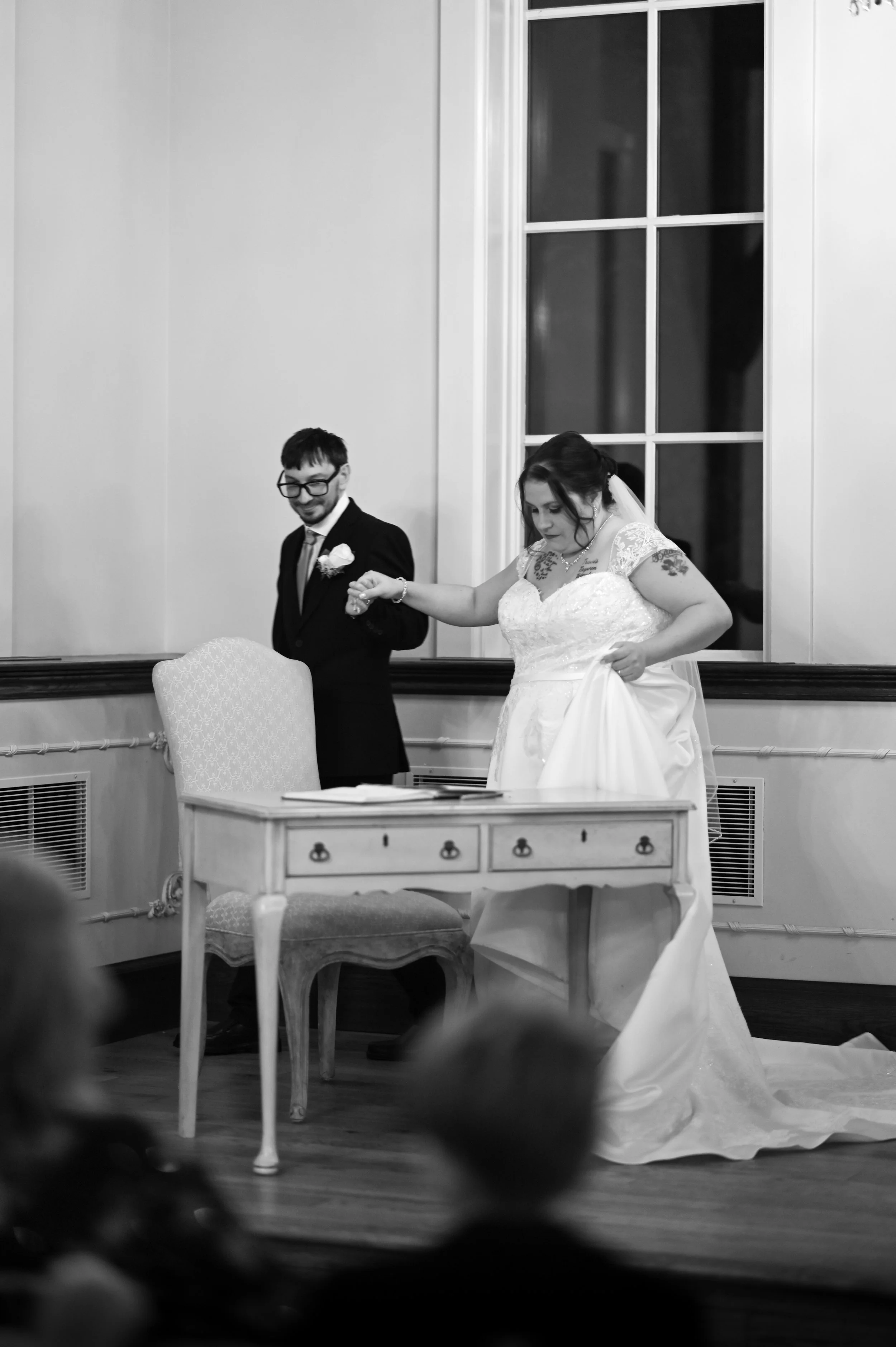 Bride and groom holding hands during wedding ceremony, bride in wedding dress and groom in suit, in a decorated indoor setting.