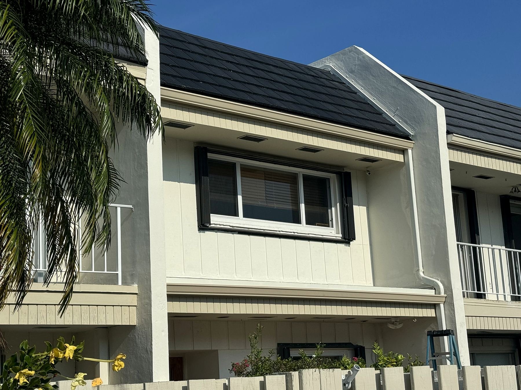 Gutter and downspout running down a two-story Miami townhouse wall