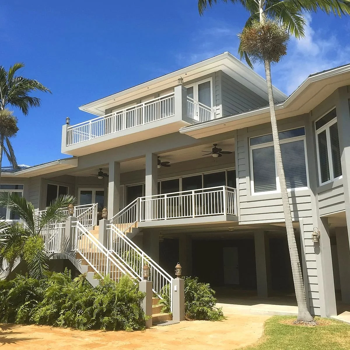 Elevated South Florida coastal home with a standing-seam metal roof, deep overhangs and a covered lanai