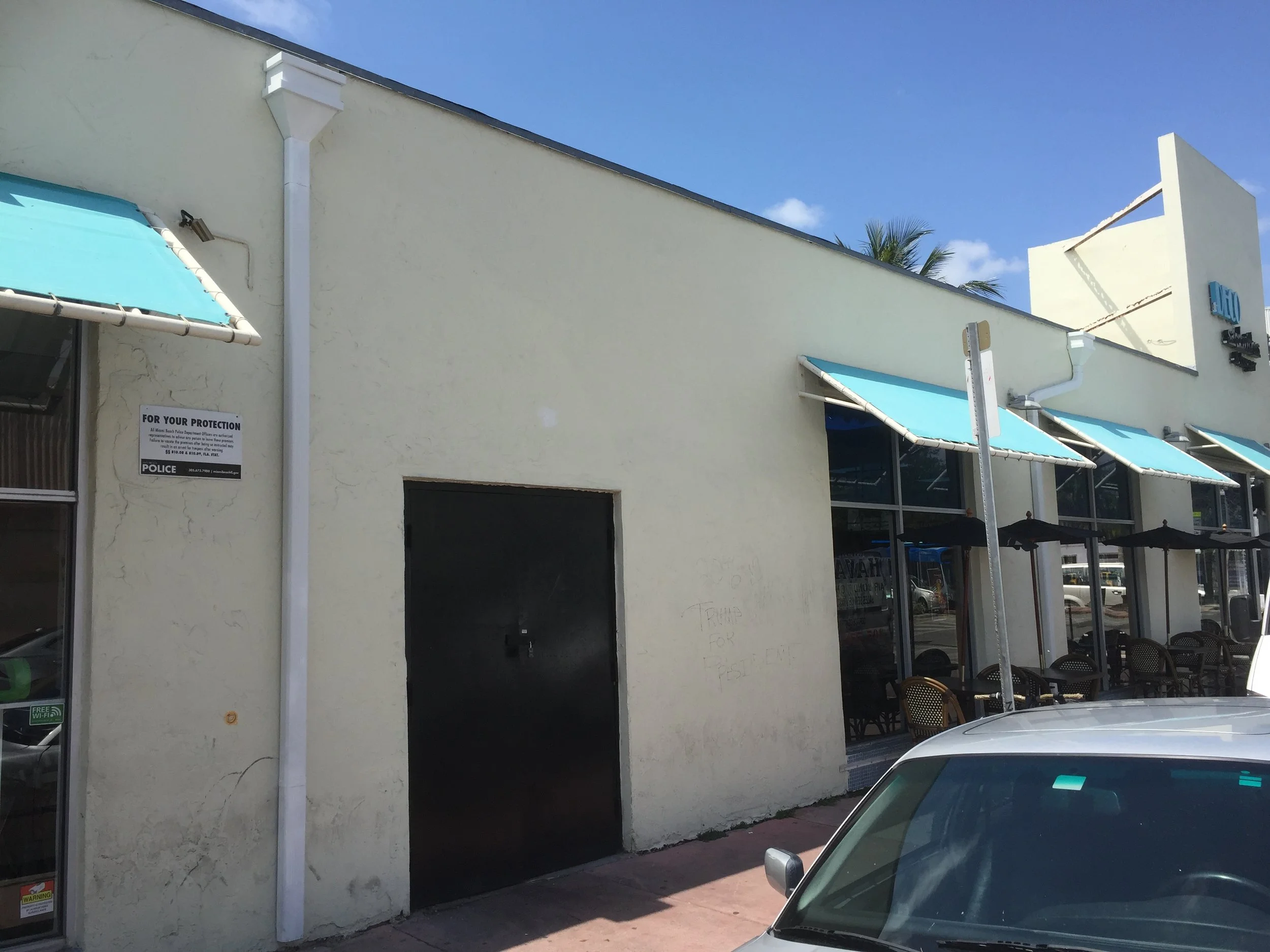 White commercial downspout and roofline on a Miami Beach retail building with awnings