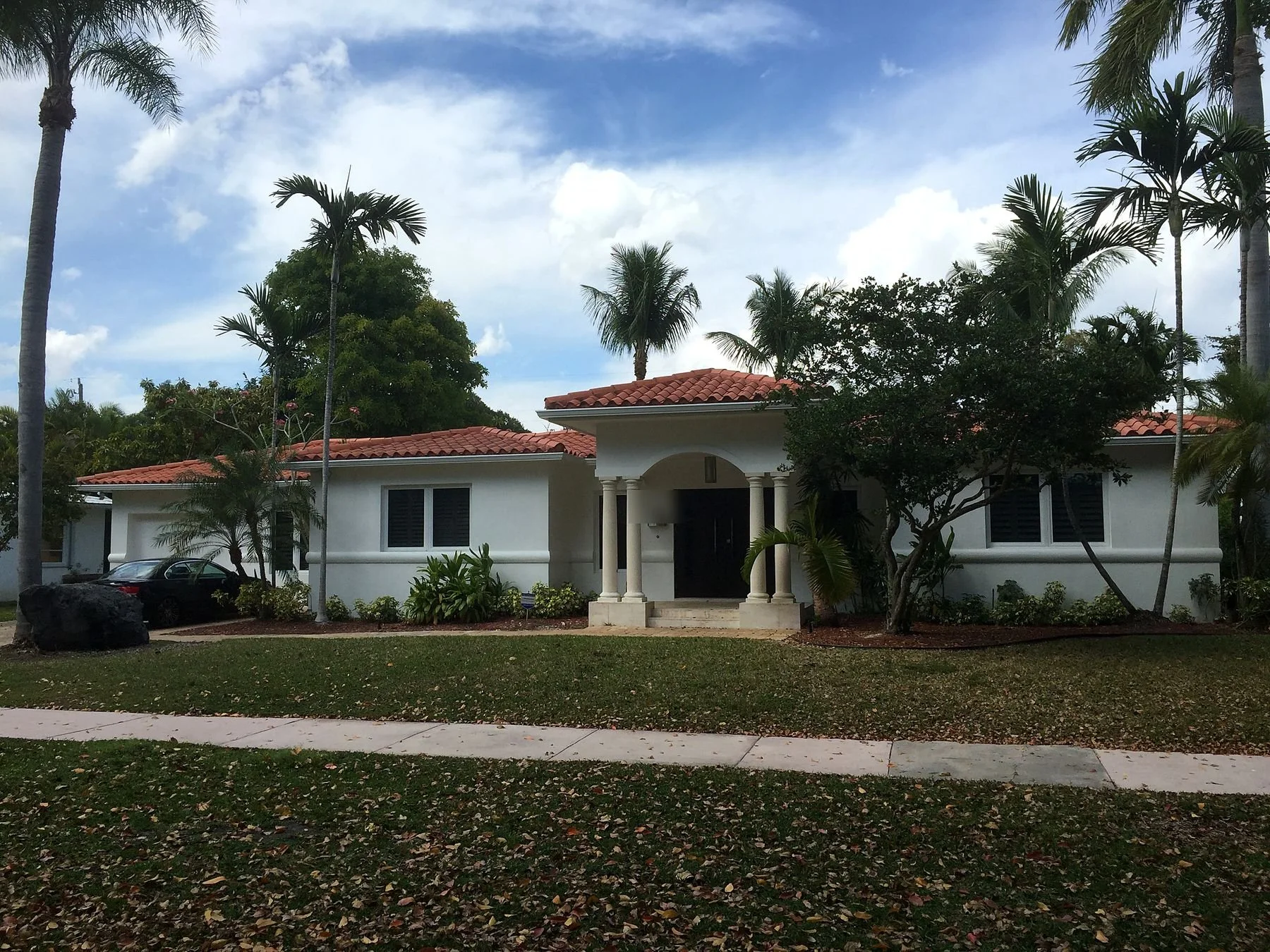 Seamless gutters on a tile-roof home in Coconut Grove surrounded by palms and shade trees