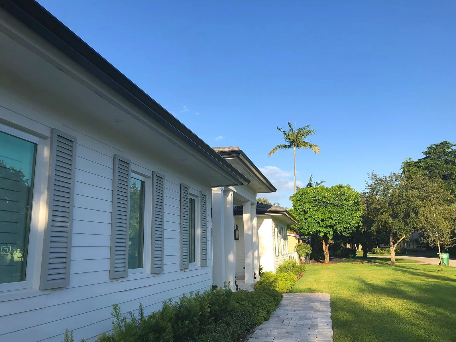 Dark bronze seamless aluminum gutter running the full length of a white siding roofline on a Miami home