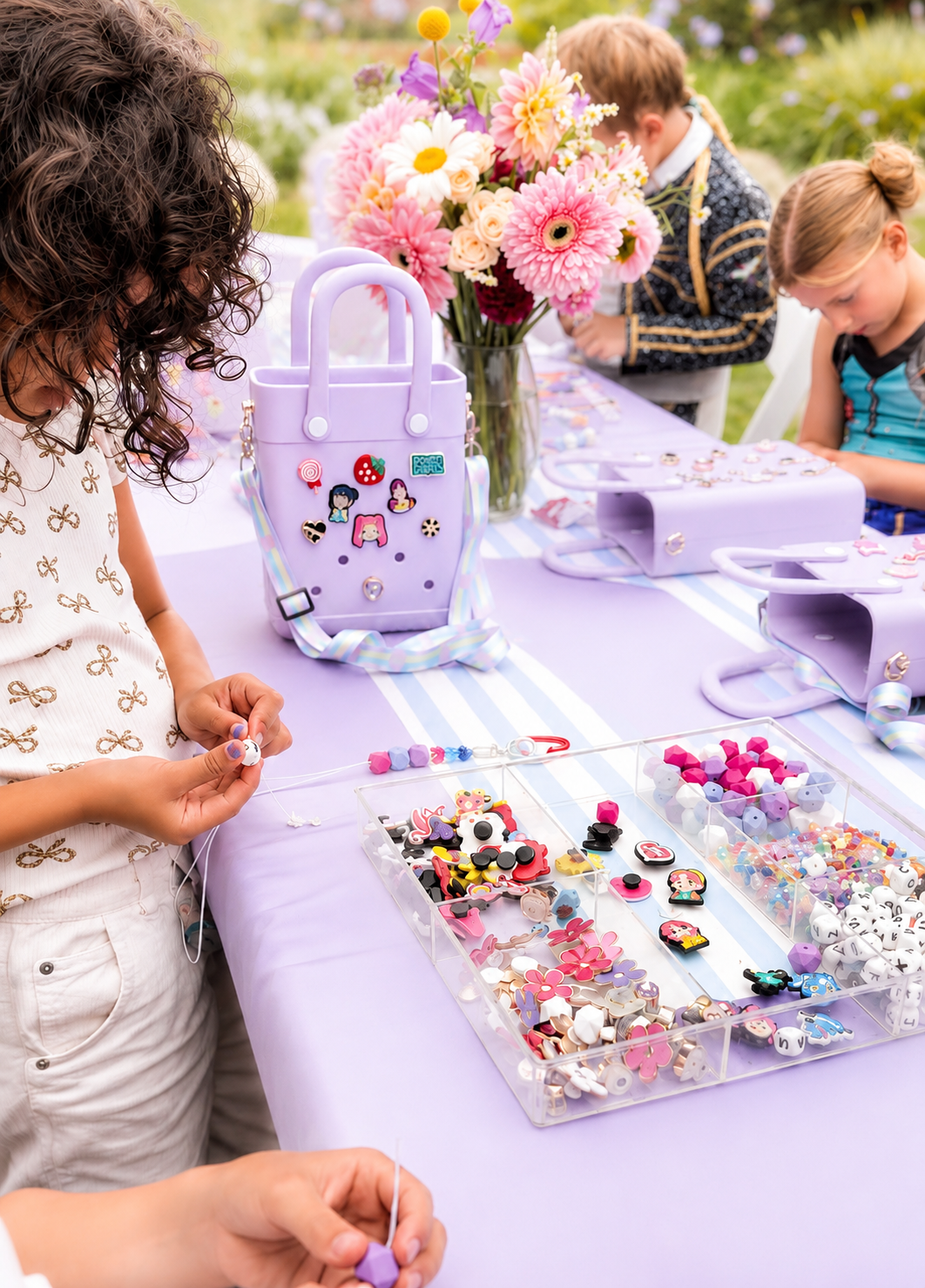 A child is decorating a denim jacket with pink heart, rainbow, and flower patches.