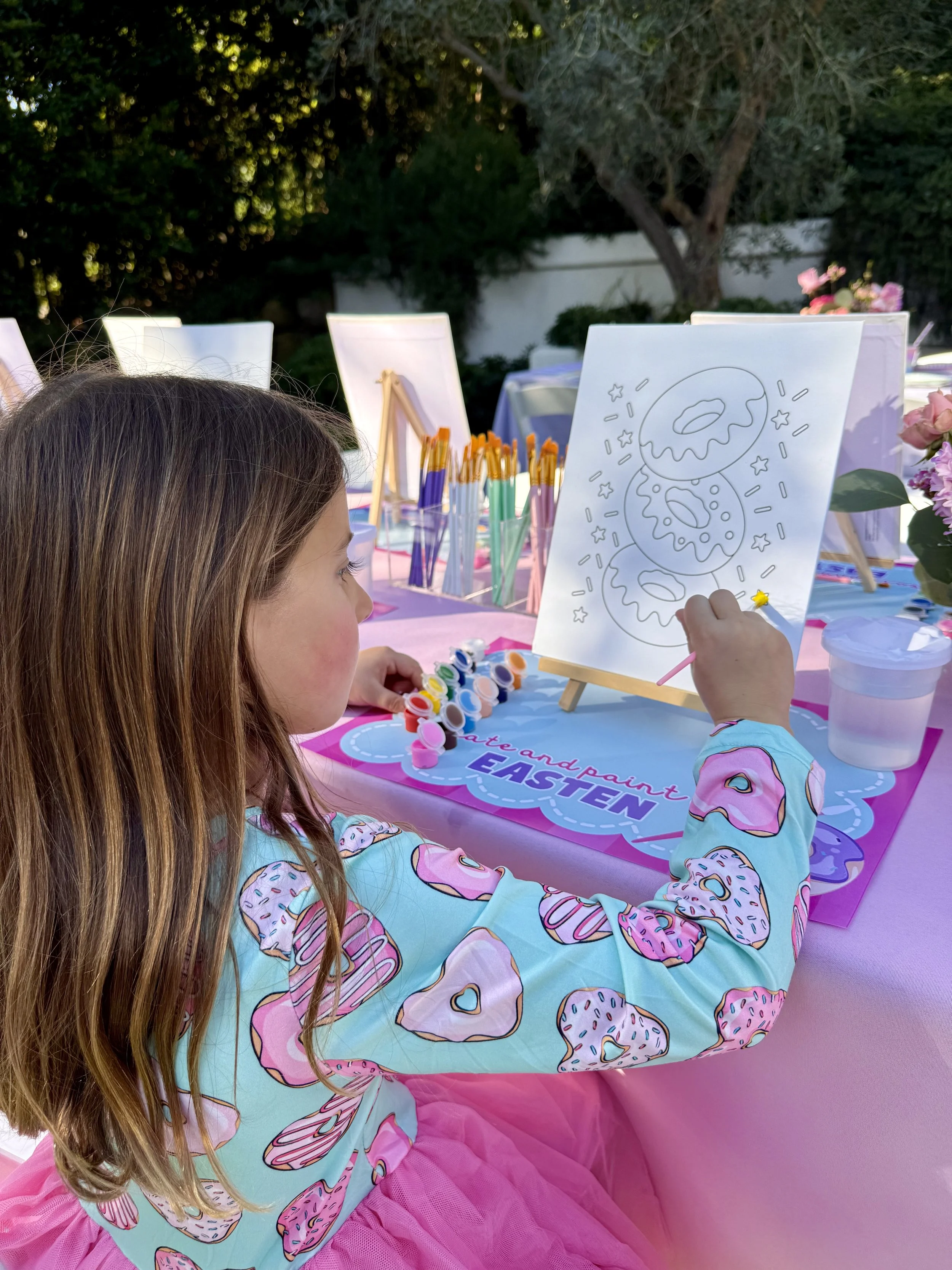 A child is decorating a denim jacket with pink heart, rainbow, and flower patches.