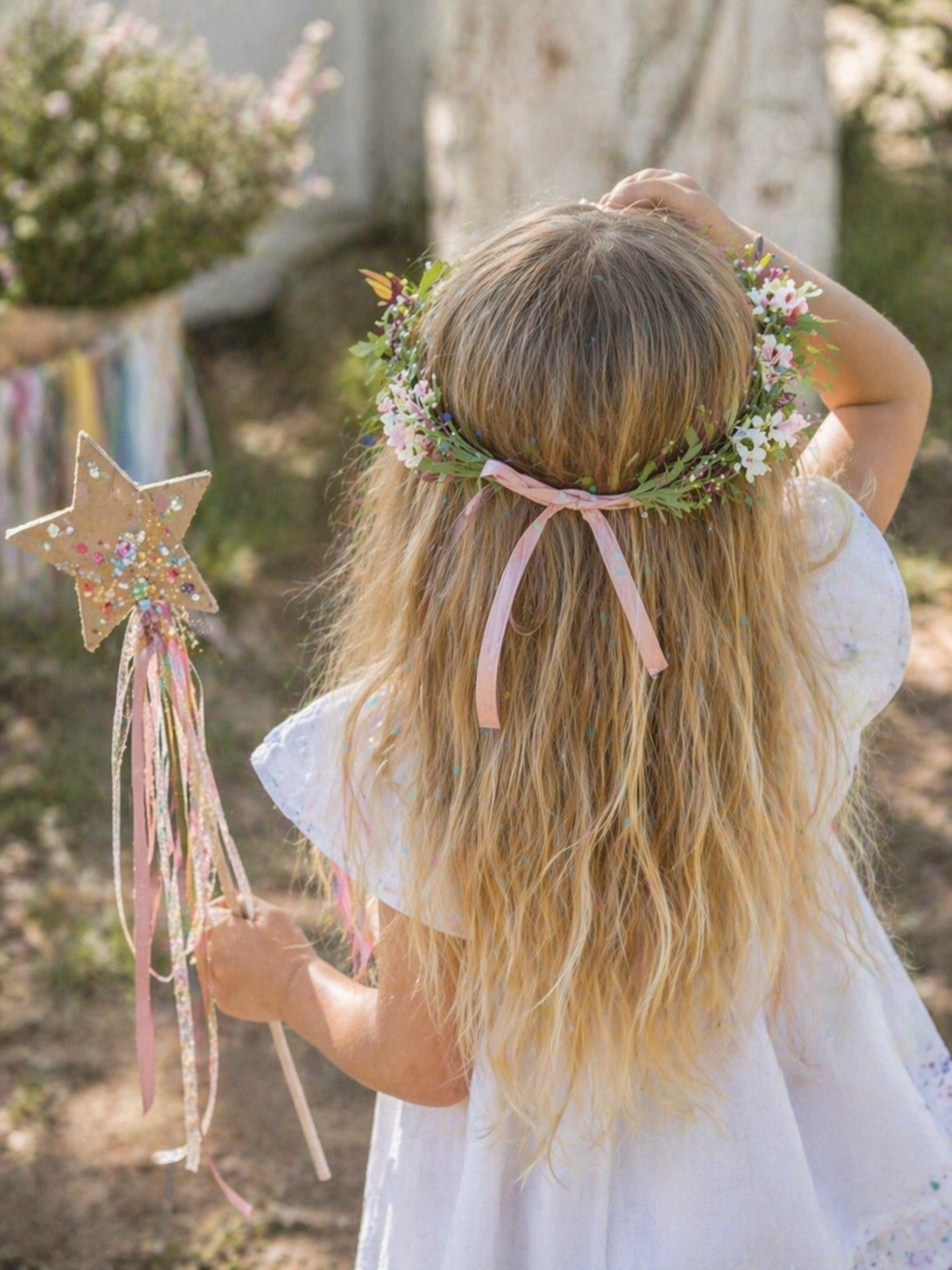 A colorful display of fairy crowns and princess wands with flowers, ribbons, and sparkle decorations suitable for a workshop.