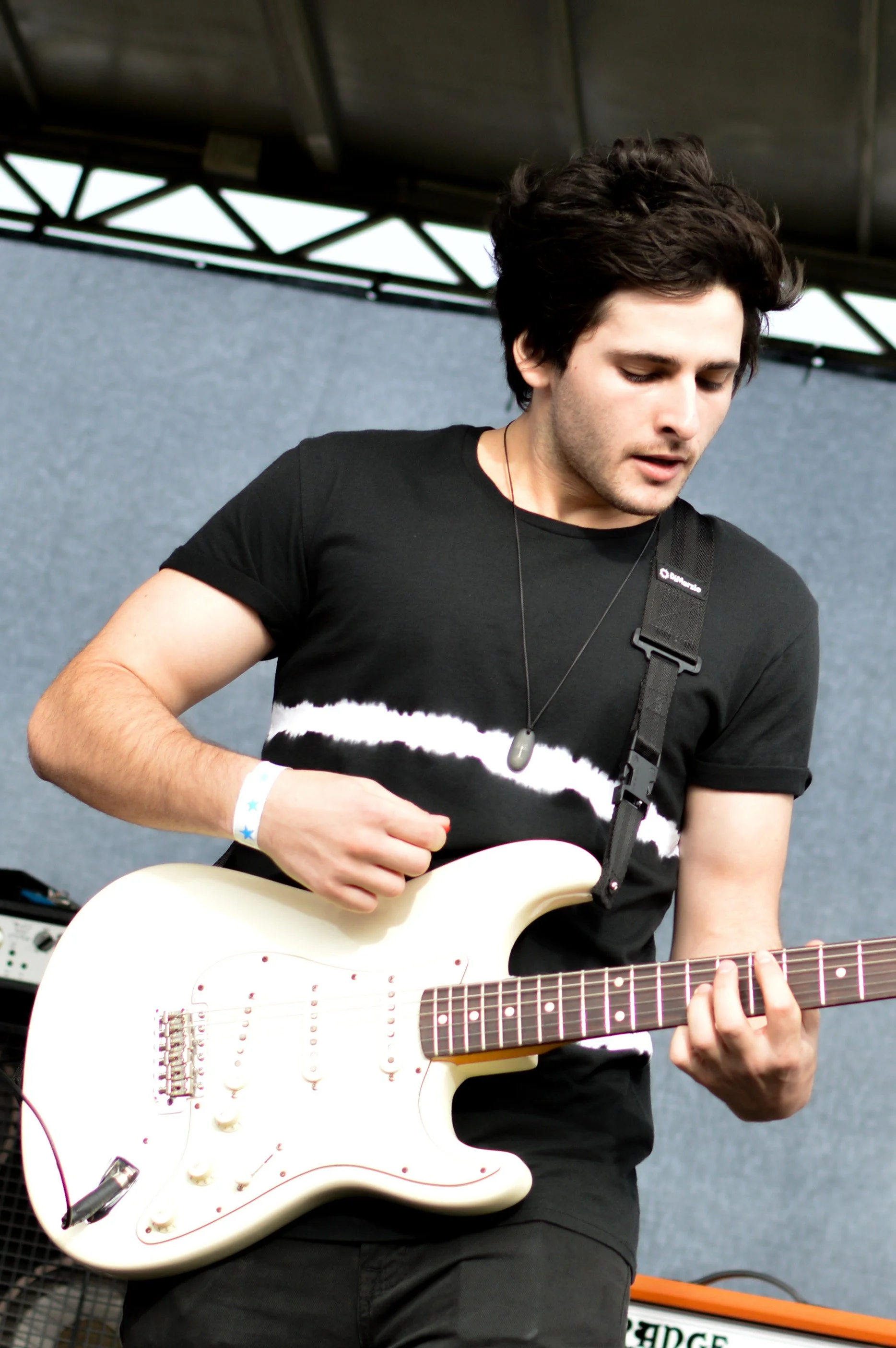 A young man playing an electric guitar on stage during a performance.