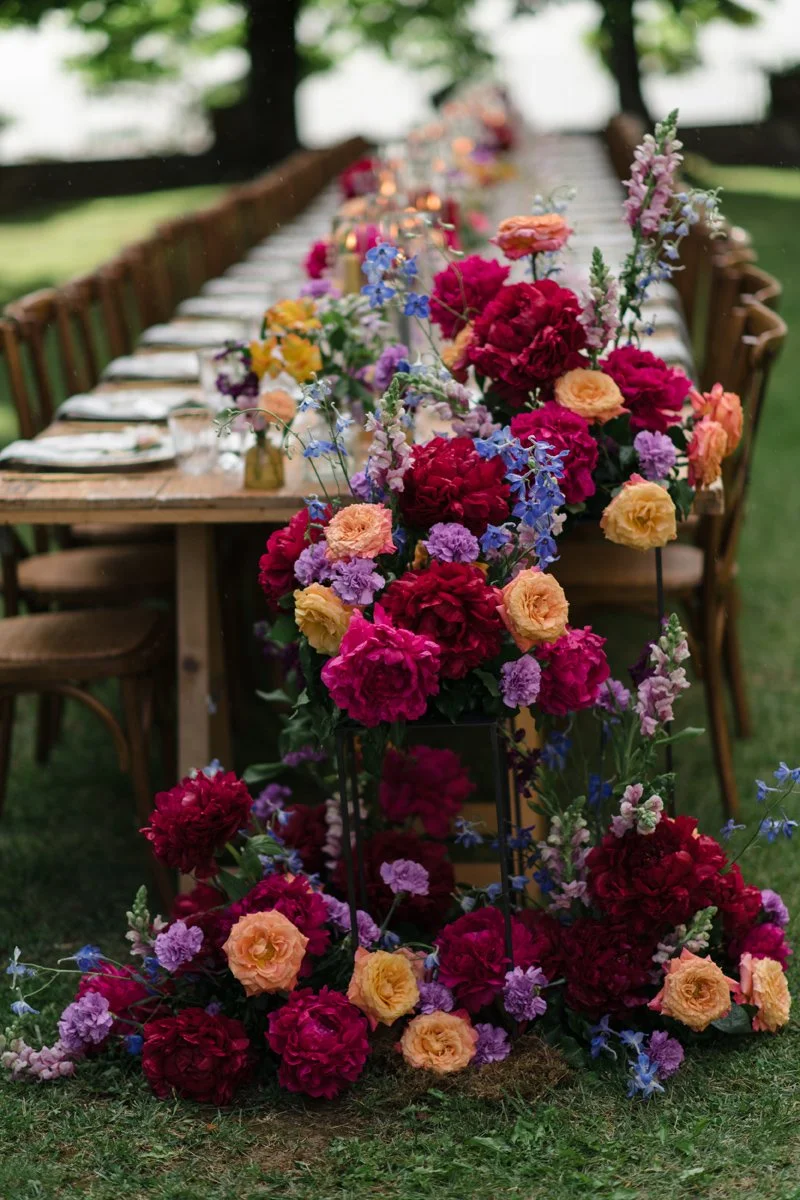 Lush floral arrangement at the end of a dinner table at Castello di Meleto, luxurious styling with seasonal flowers by FunkyBird for elegant weddings in Tuscany.