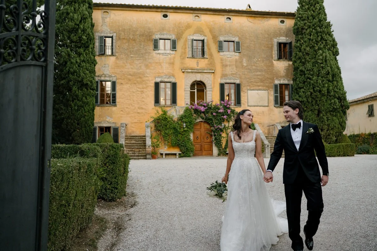 Couple walking together in front of Villa di Ulignano in Tuscany, showing how classic villa venues offer elegant structure and smooth transitions for guests throughout the wedding day.