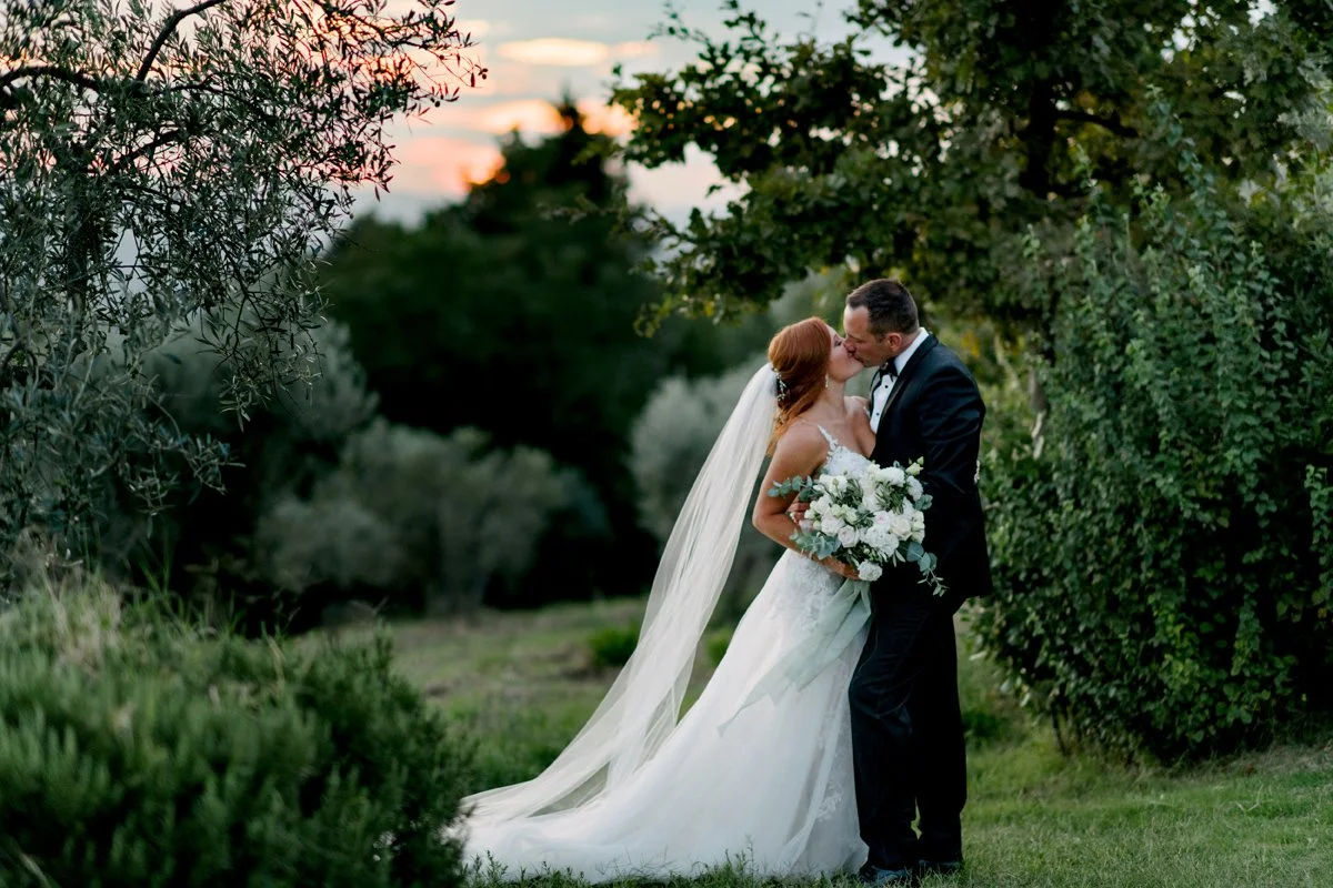 Romantic kiss in the Tuscan countryside at Borgo Petrognano , a heartfelt moment from a beautifully planned wedding in Italy by FunkyBird Weddings.