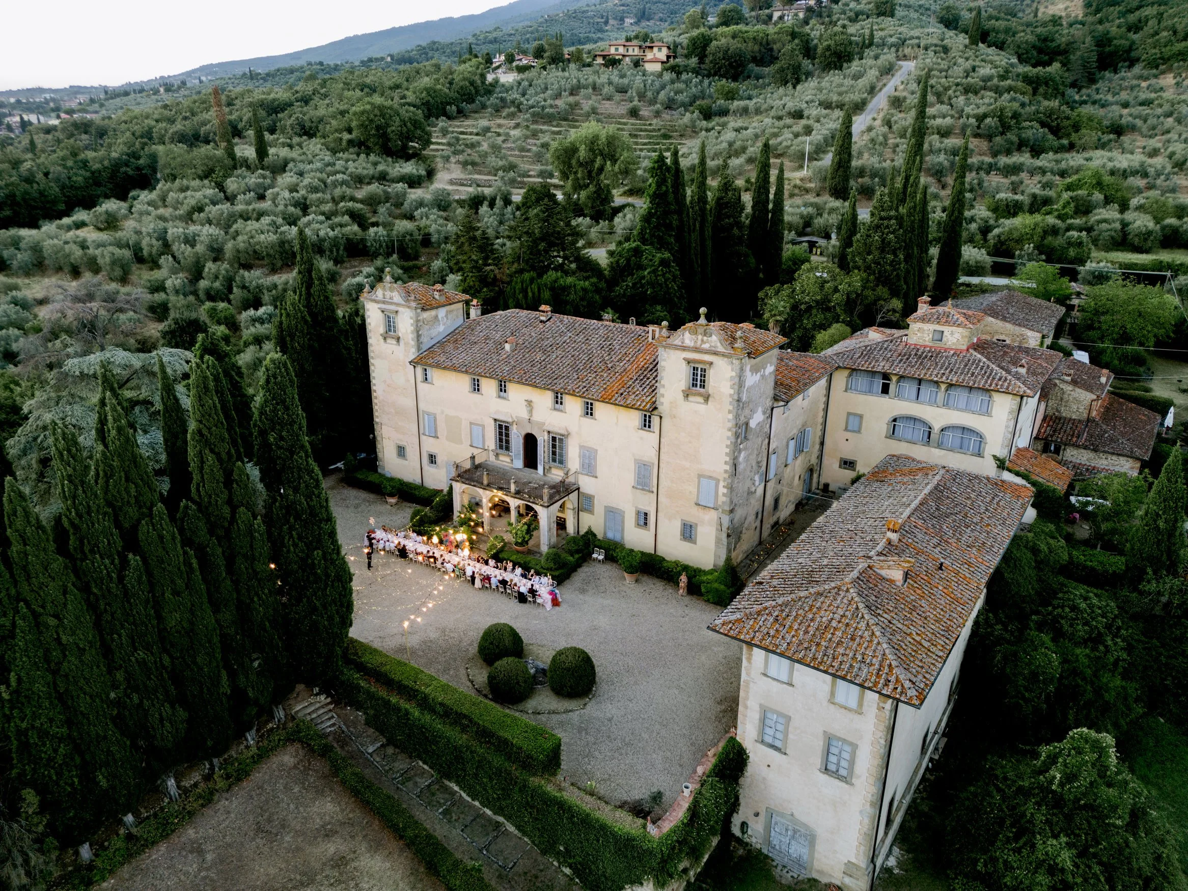 Drone view of a long table wedding dinner at Villa Medicea in Tuscany, showing how panoramic villa venues shape guest experience through shared dining, landscape, and atmosphere.