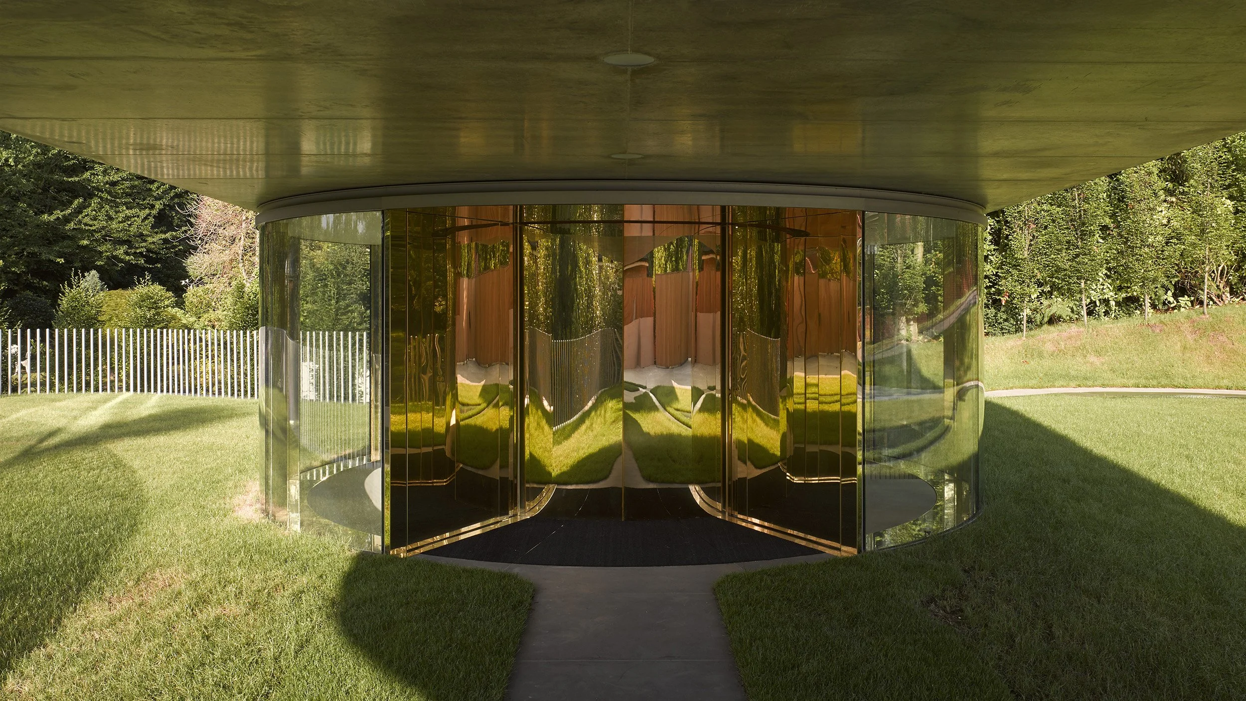 Reflective glass structure with grassy surroundings