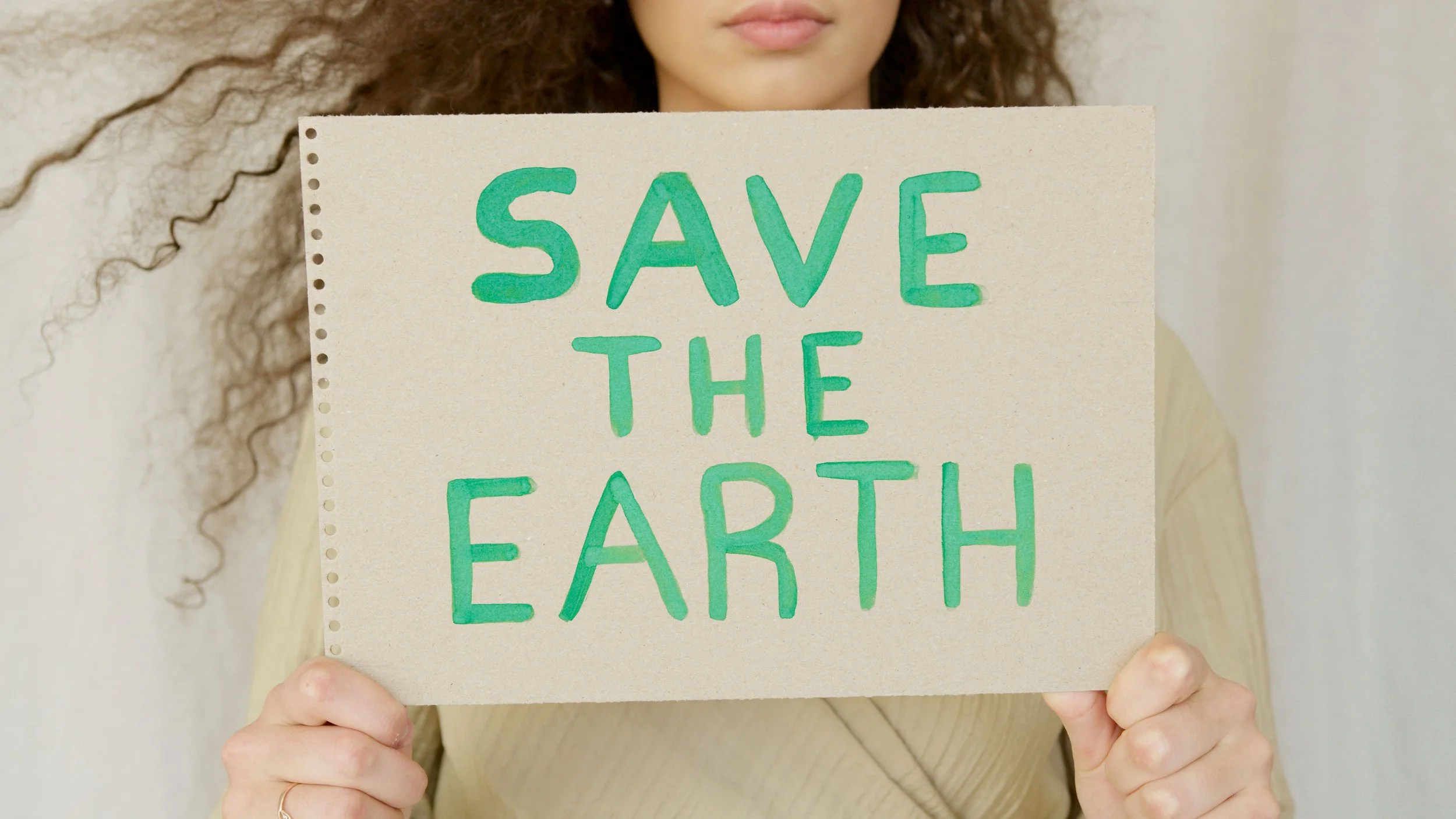 Image of a woman holding a sign that says "Save the Earth".