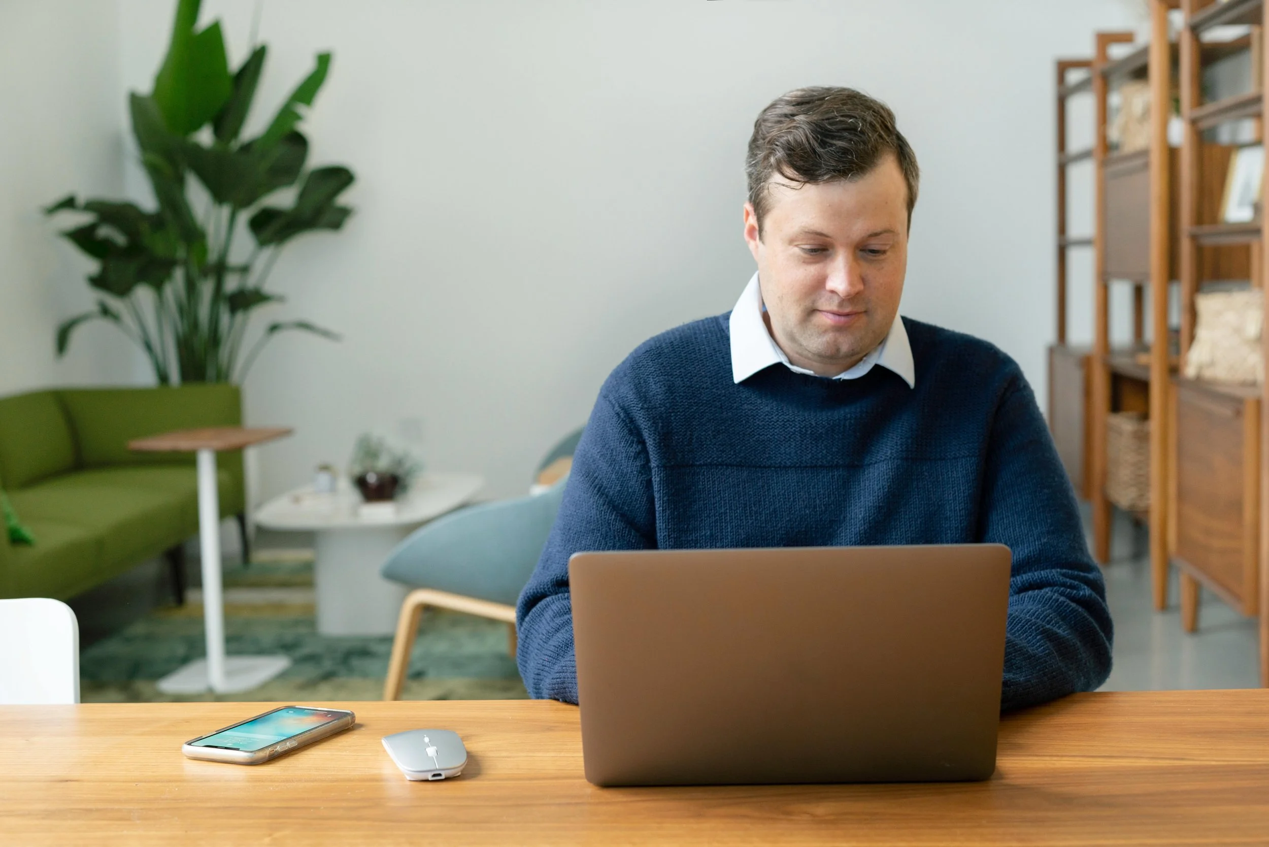 Man wearing a blue sweater using a laptop.