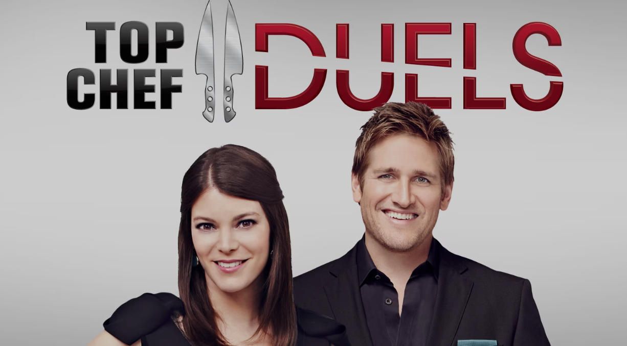 Title card for Top Chef Duels featuring a man and woman in black attire smiling, with the show's logo including large text and a chef's knife.