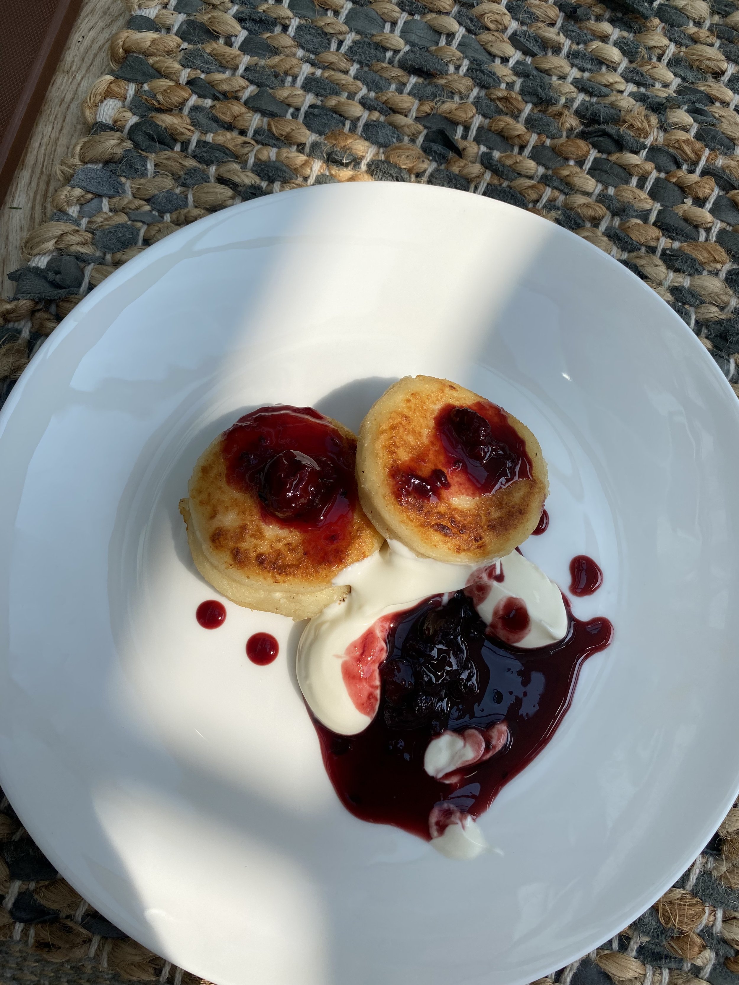 Ukrainian Sirniki (cheese pancakes) served with sour cream and homemade sour cherry compote