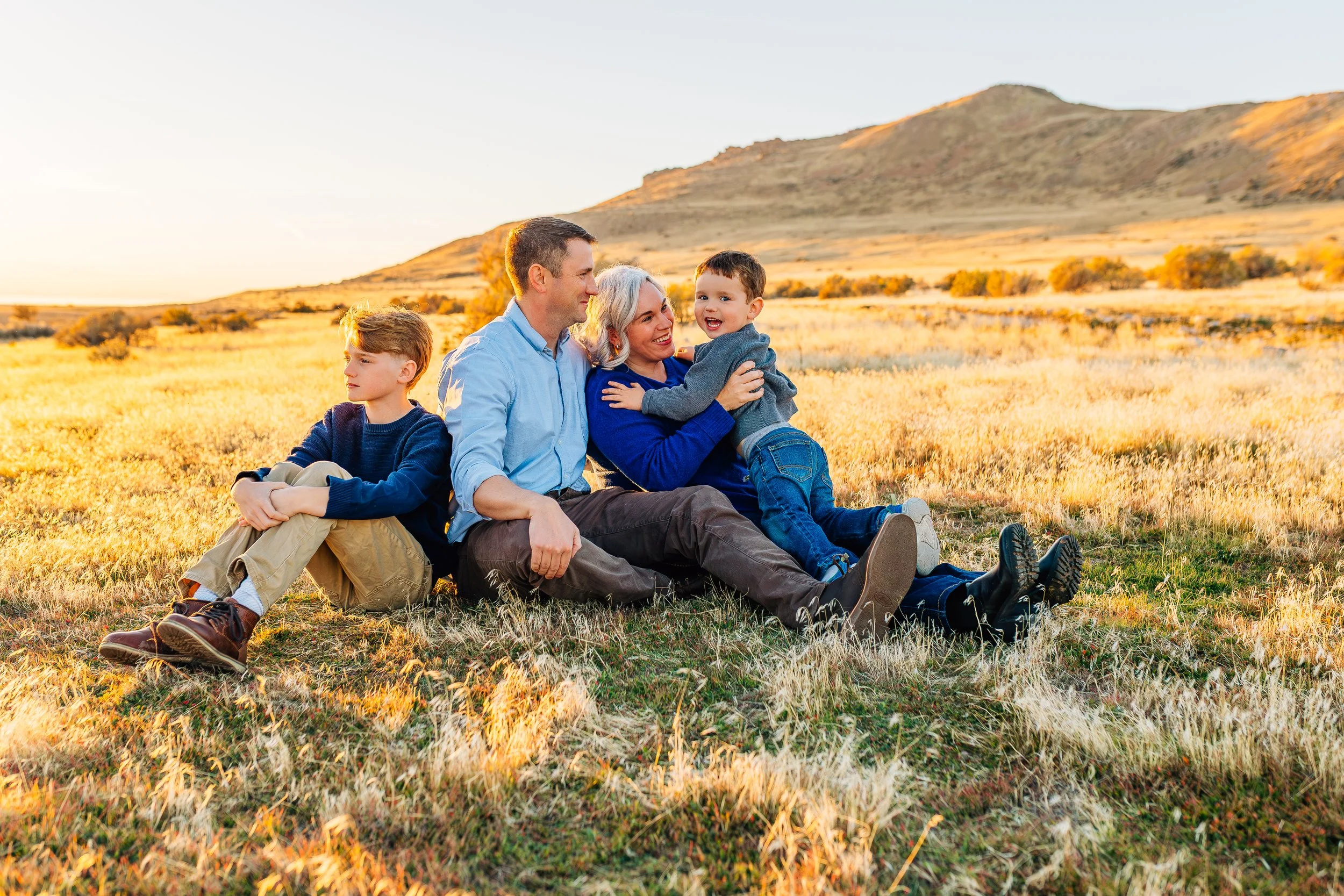 Family sitting together in a field during a winter family photography session at Antelope Island in Utah