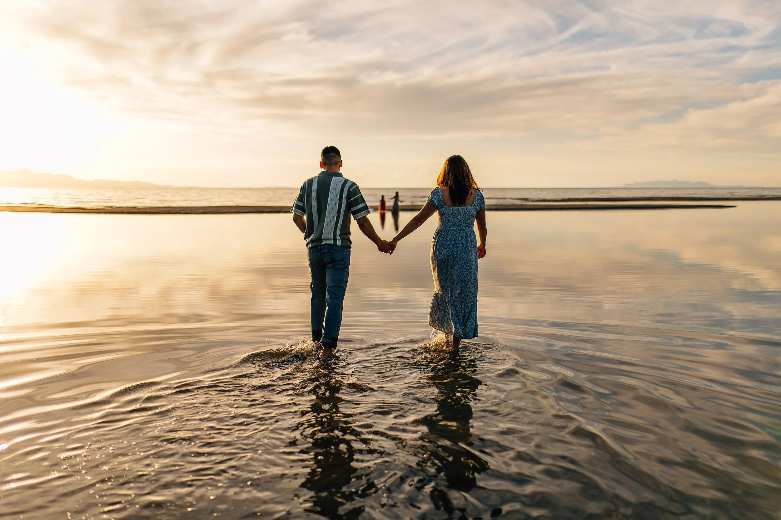 A couple holding hands while walking through shallow water at the Great Salt Lake in Utah at sunset