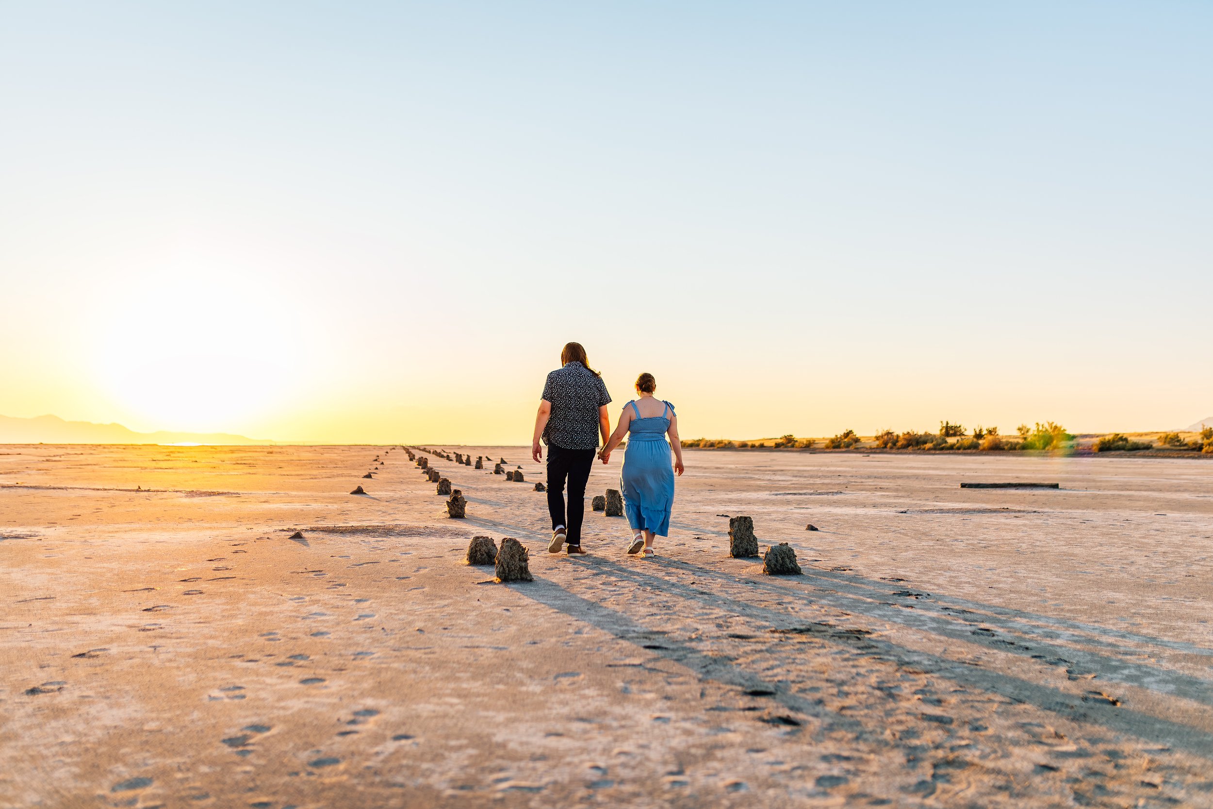 Couple walking across the exposed lakebed near the remnants of an old pier at the Great Salt Lake near Saltair in Utah