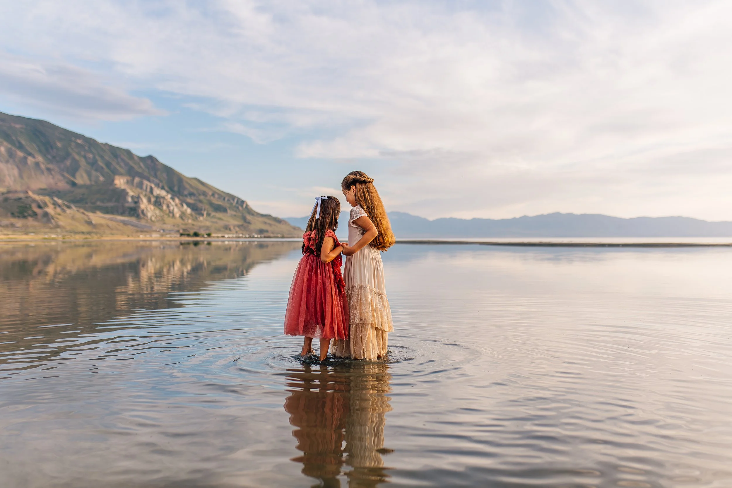 Documentary family photography in Utah capturing two children standing together in shallow water at the Great Salt Lake
