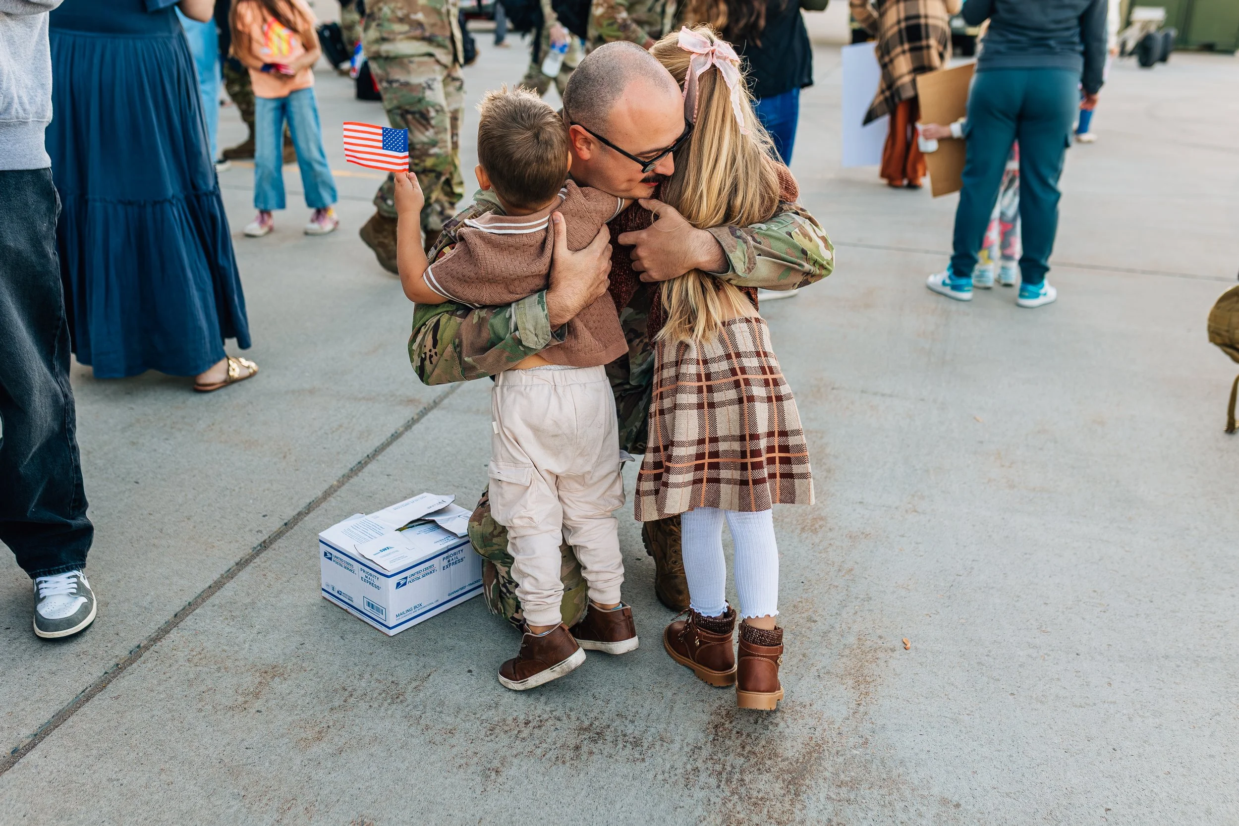Documentary family photograph of a military parent reuniting with children during a homecoming event in Utah