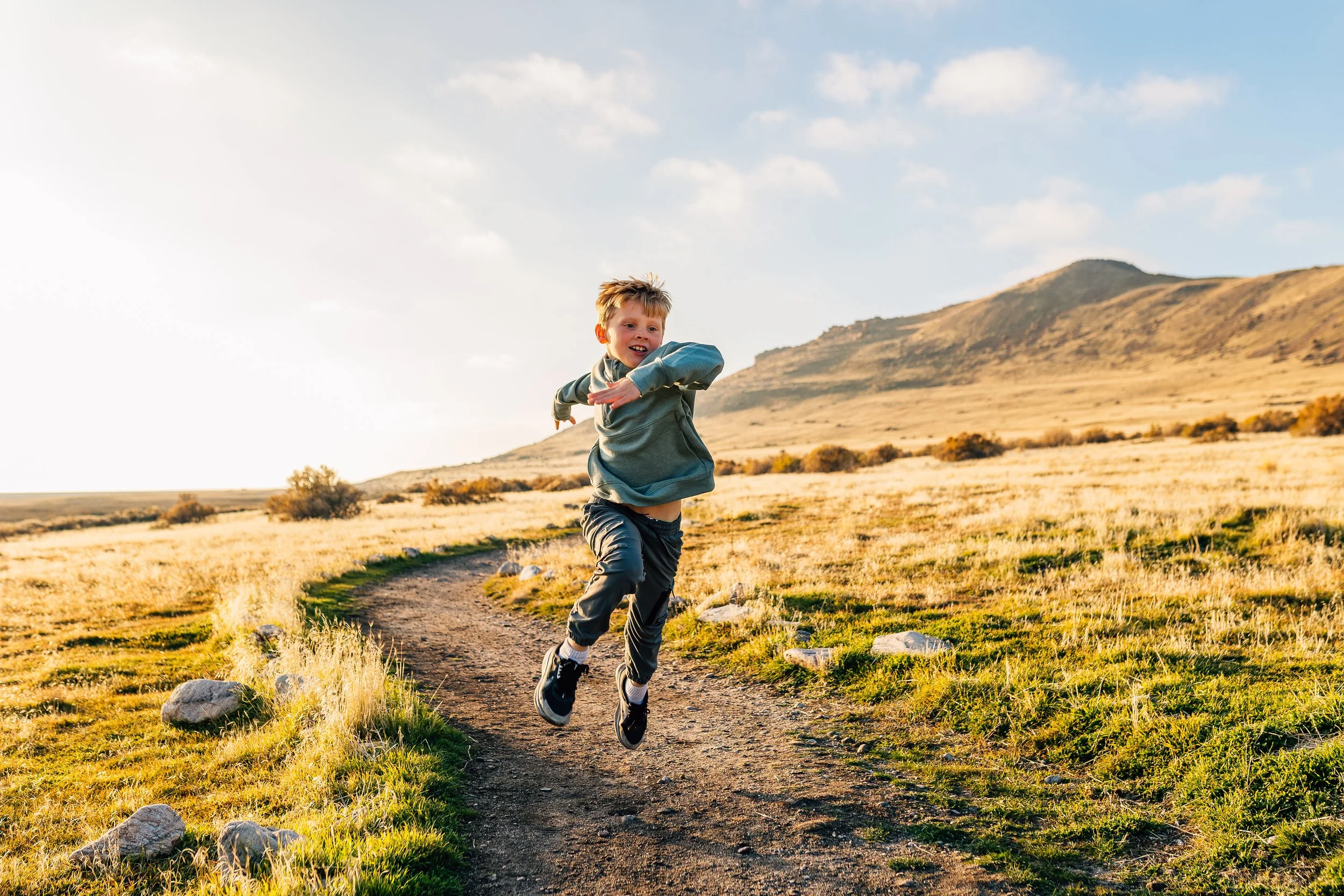 Child jumping on a trail during a winter family photo session at Antelope Island in Utah