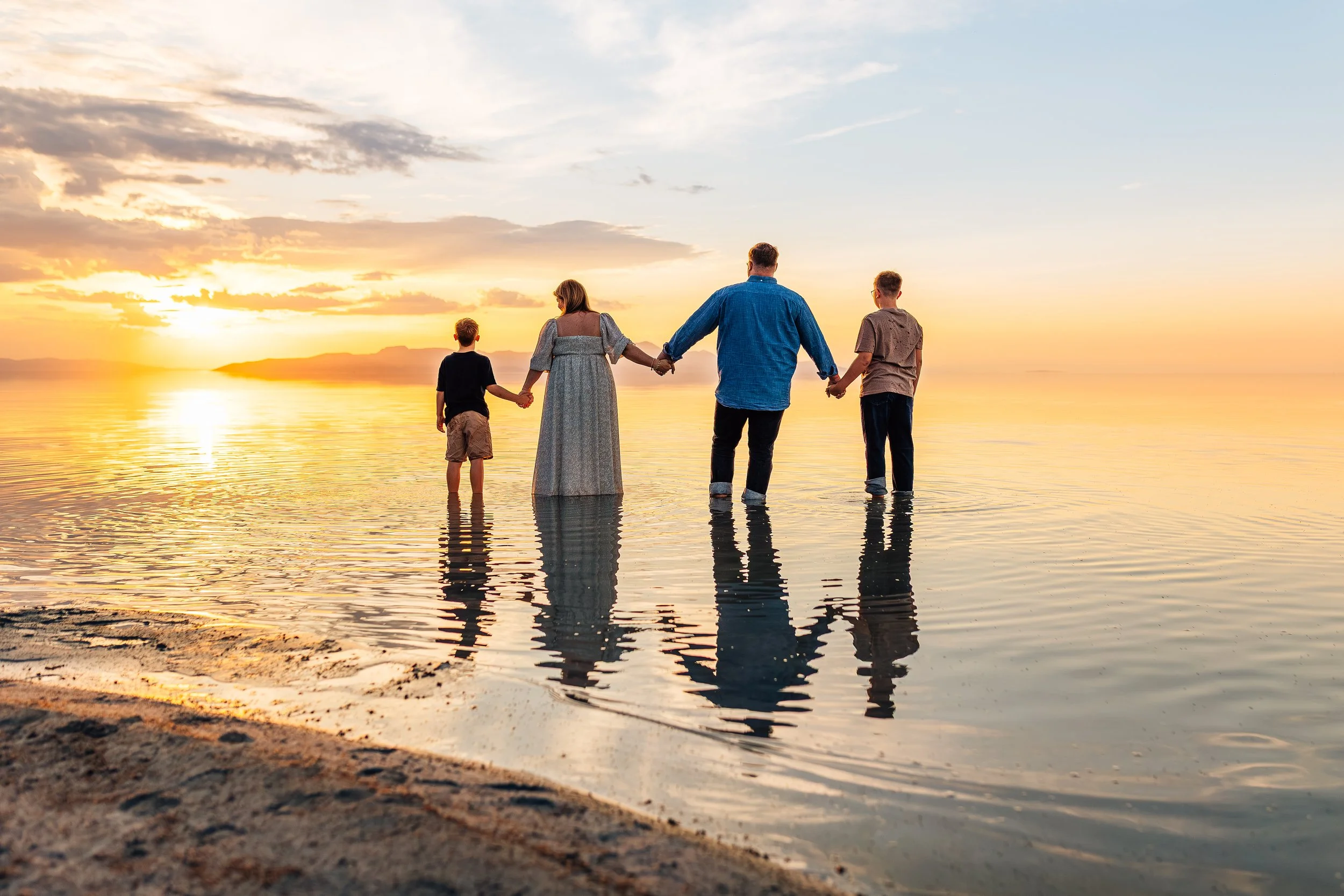 Silhouetted family holding hands during a sunset session at the Great Salt Lake in Salt Lake County, Utah, captured in documentary-style family photography.