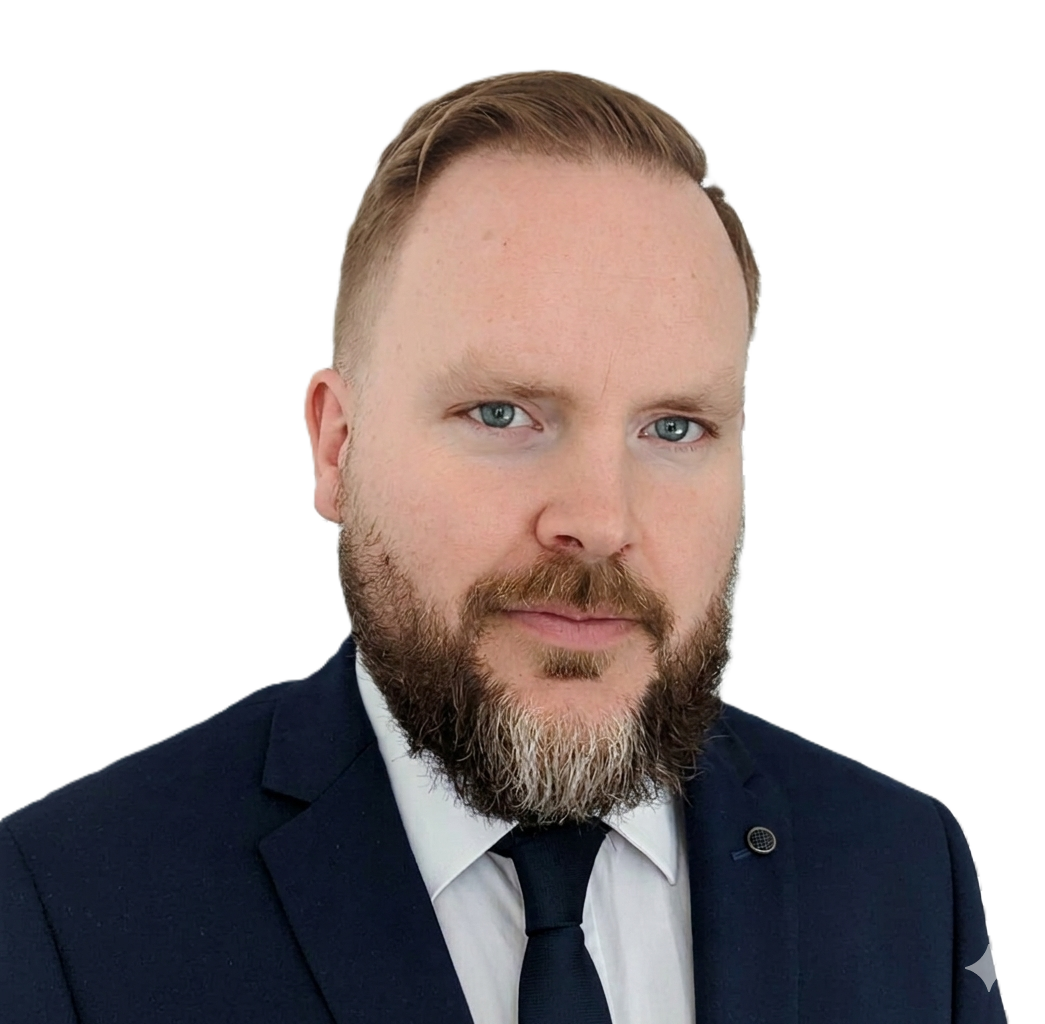Portrait of a man with a beard and blonde hair wearing a dark suit, white shirt, and dark tie.