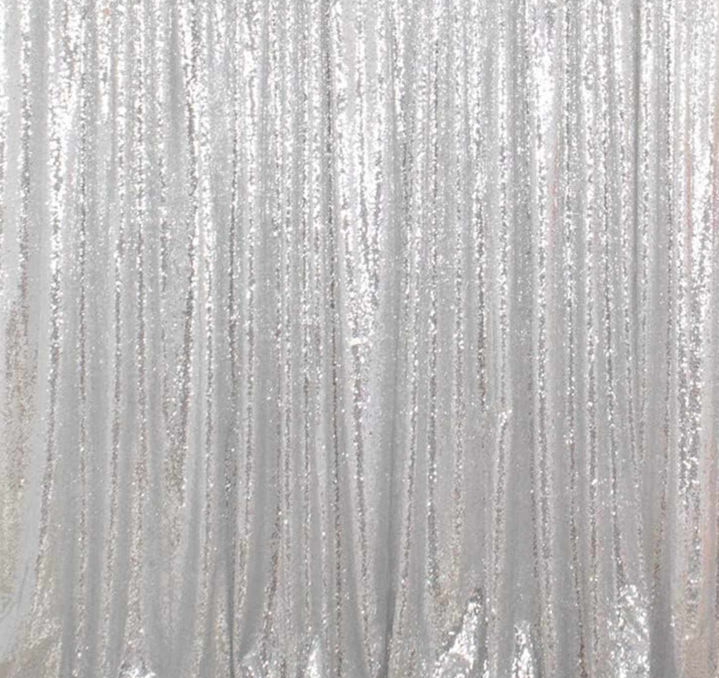 Silver glittery curtain with vertical folds and sparkles.