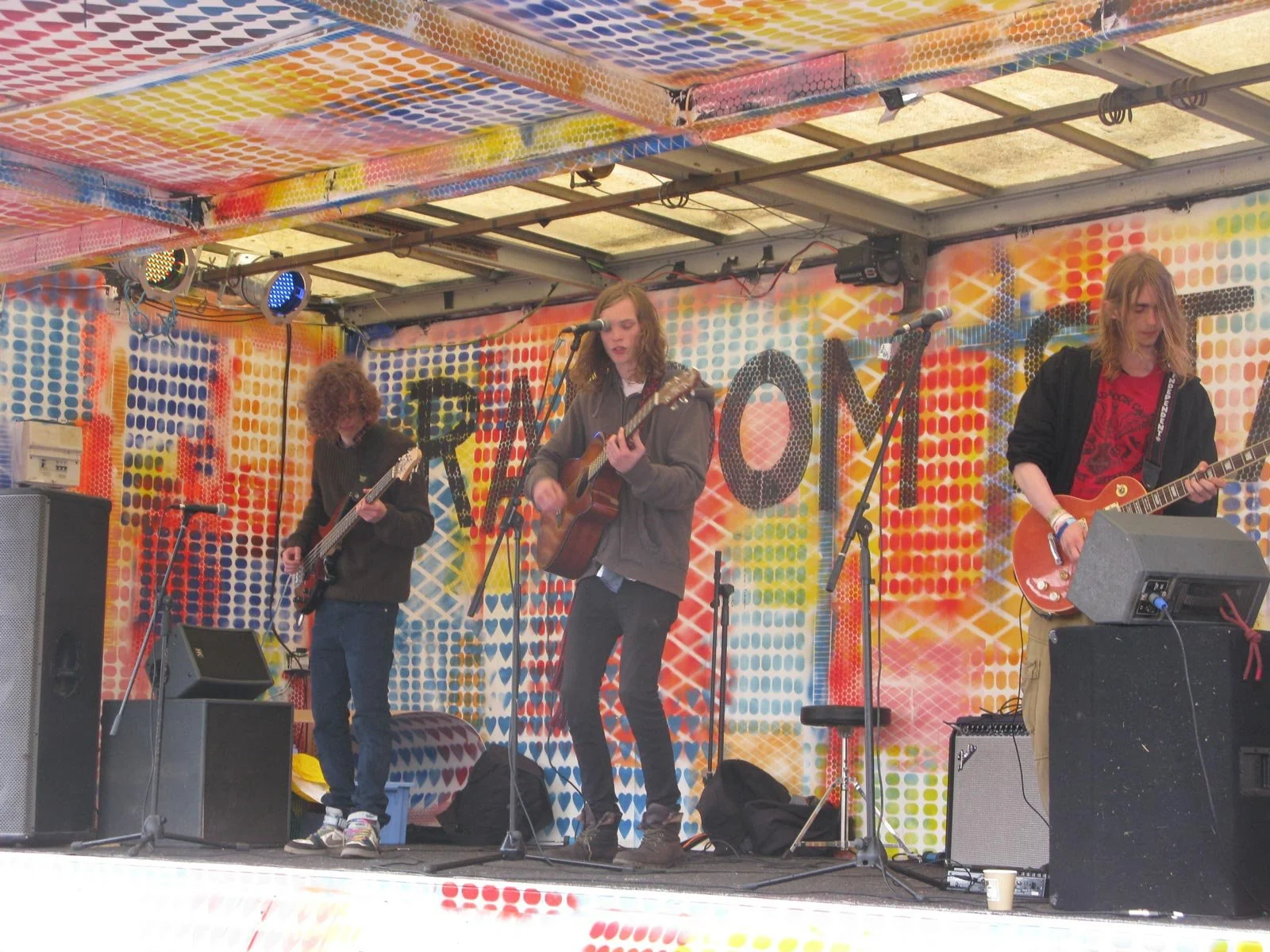 Band performing on a colorful stage with guitars and speakers.