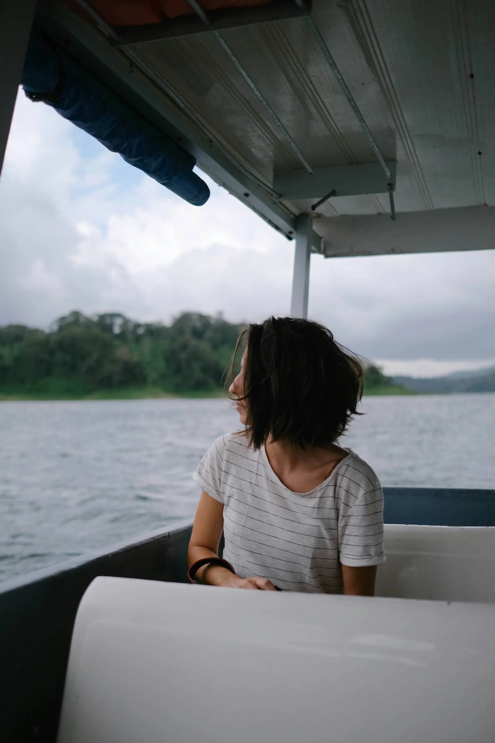 A woman with short hair sits on a boat, looking beyond