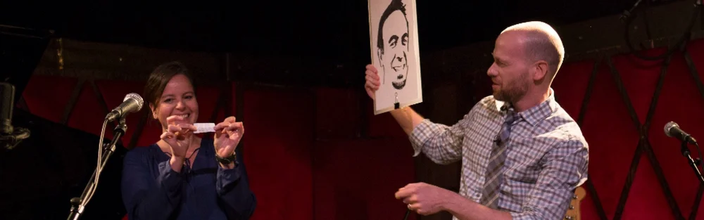 Mentalist Fred Berthelot holding up a portrait drawing during his stage show