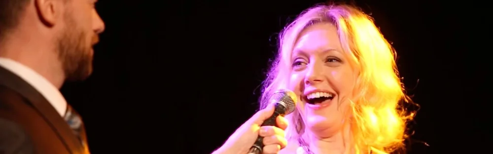 Volunteer laughing as mentalist Fred Berthelot holds the microphone on stage