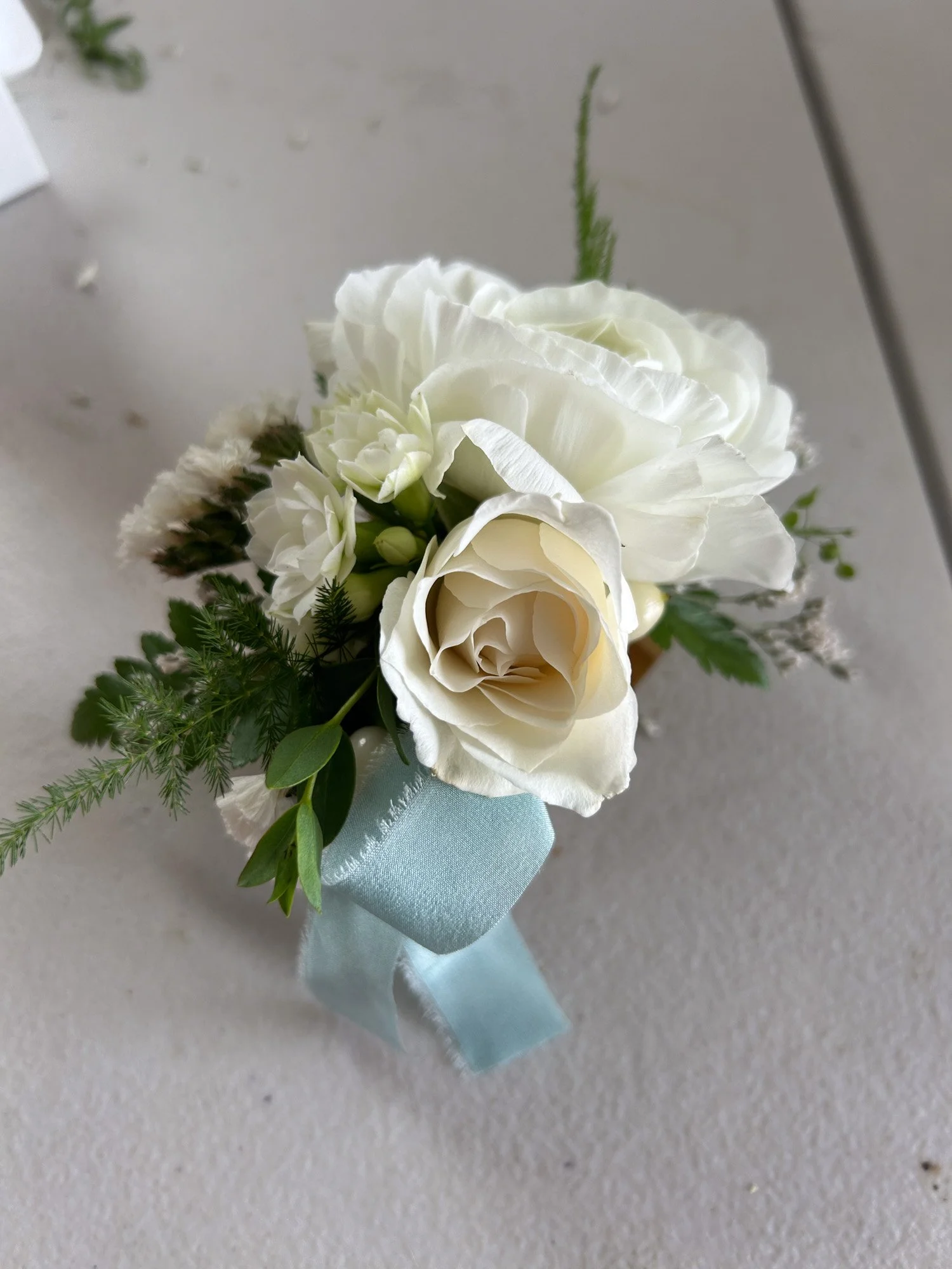 white wrist corsage with blue ribbon for school dance