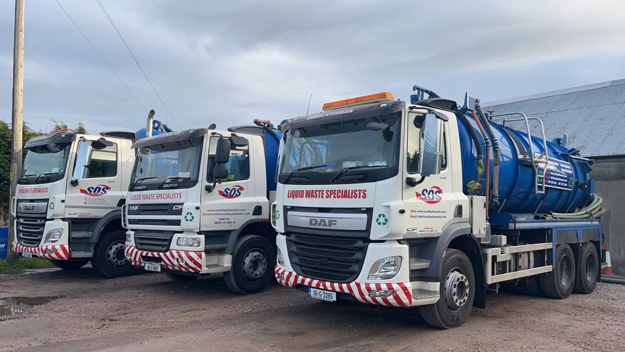 Three liquid waste disposal trucks parked side by side with company logos and contact information displayed.