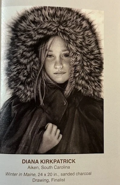 A charcoal drawing titled 'Winter in Maine' features a person wearing a heavy fur-lined hooded coat, created by Diana Kirkpatrick from Aiken, South Carolina. The artwork is a 24 x 20 inch piece and was a finalist in a competition.