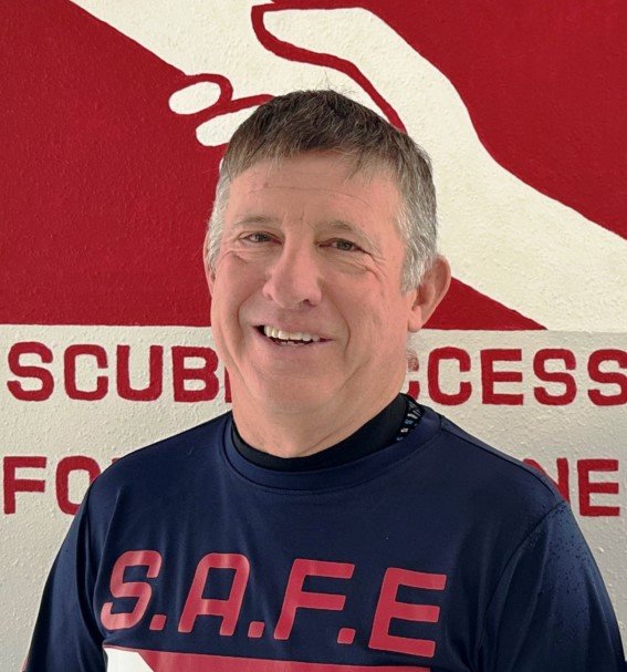 Dale smiling in front of the SAFE logo